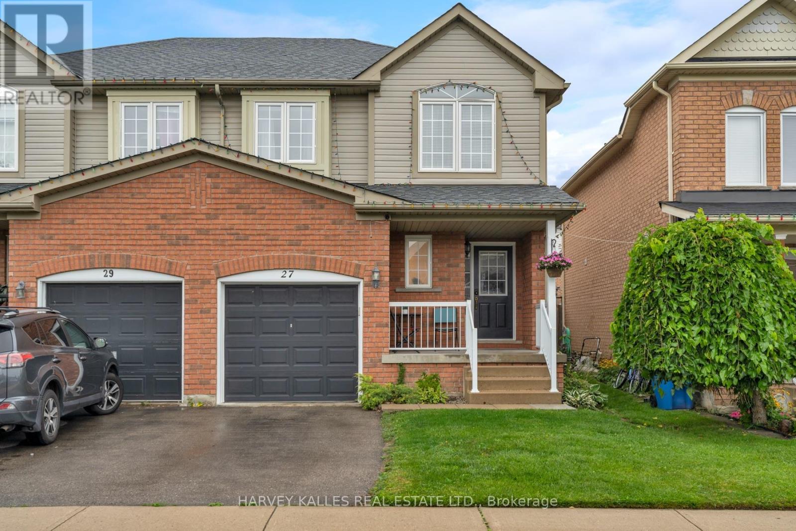 Two-storey brick and beige semi-detached house with two garage doors and a covered entrance.