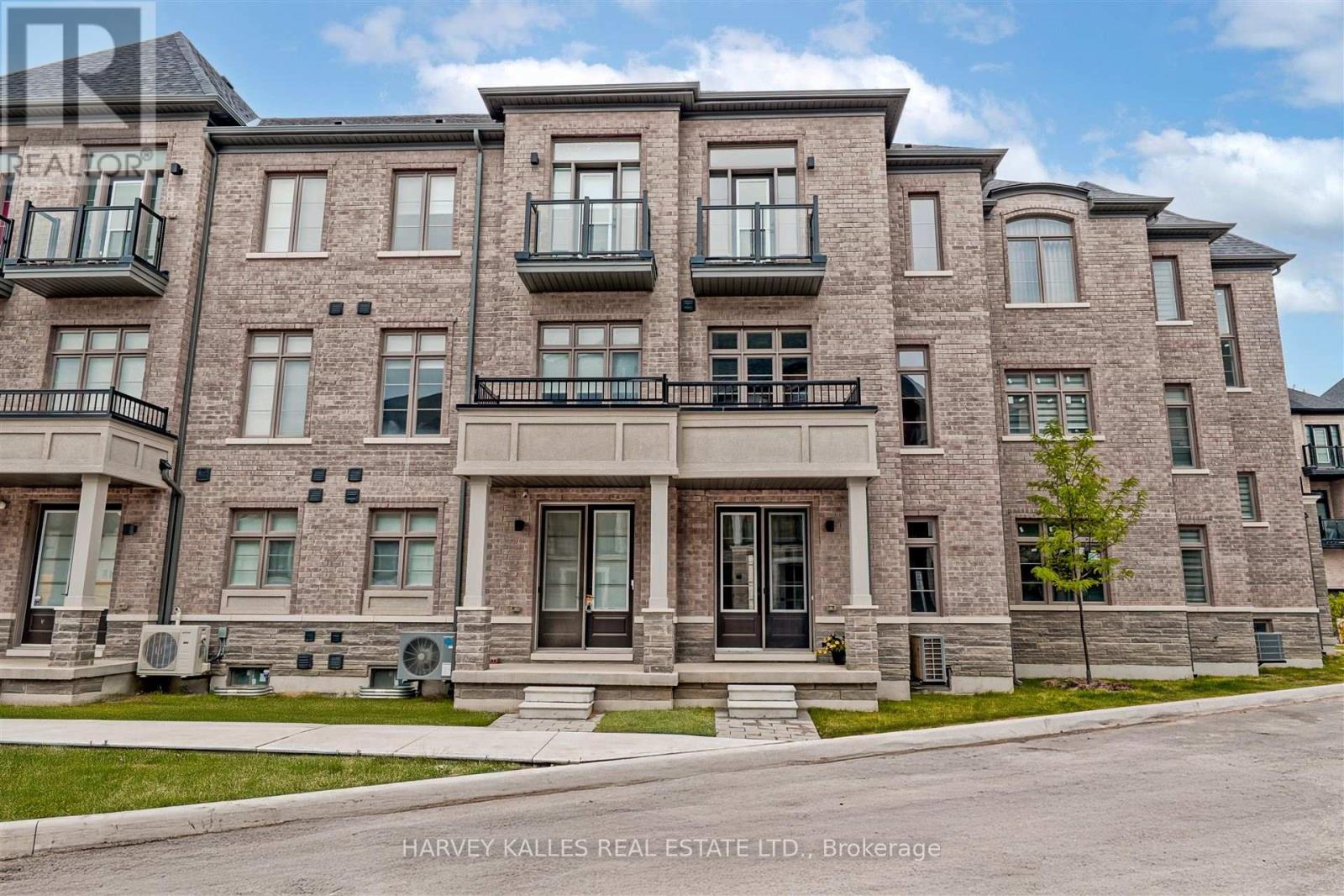 Attached brick townhomes with glass balconies and multiple front entrances.