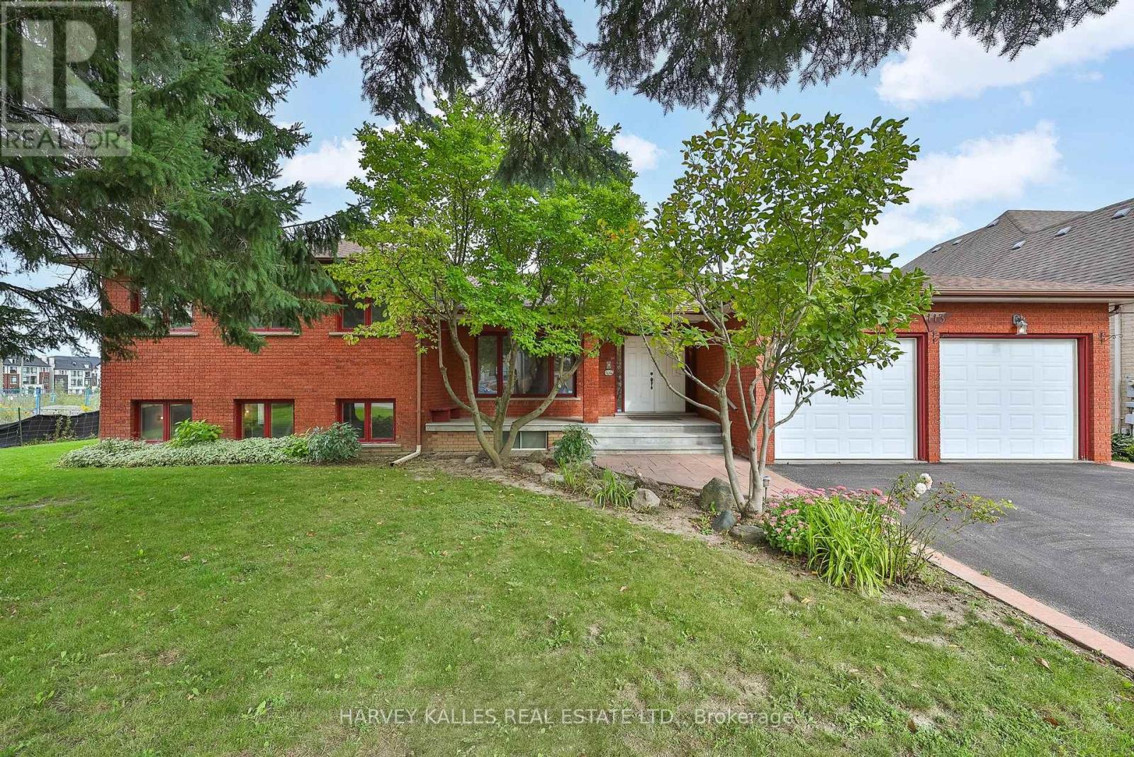 Red-brick two-storey house with a double garage, landscaped front garden and mature trees.