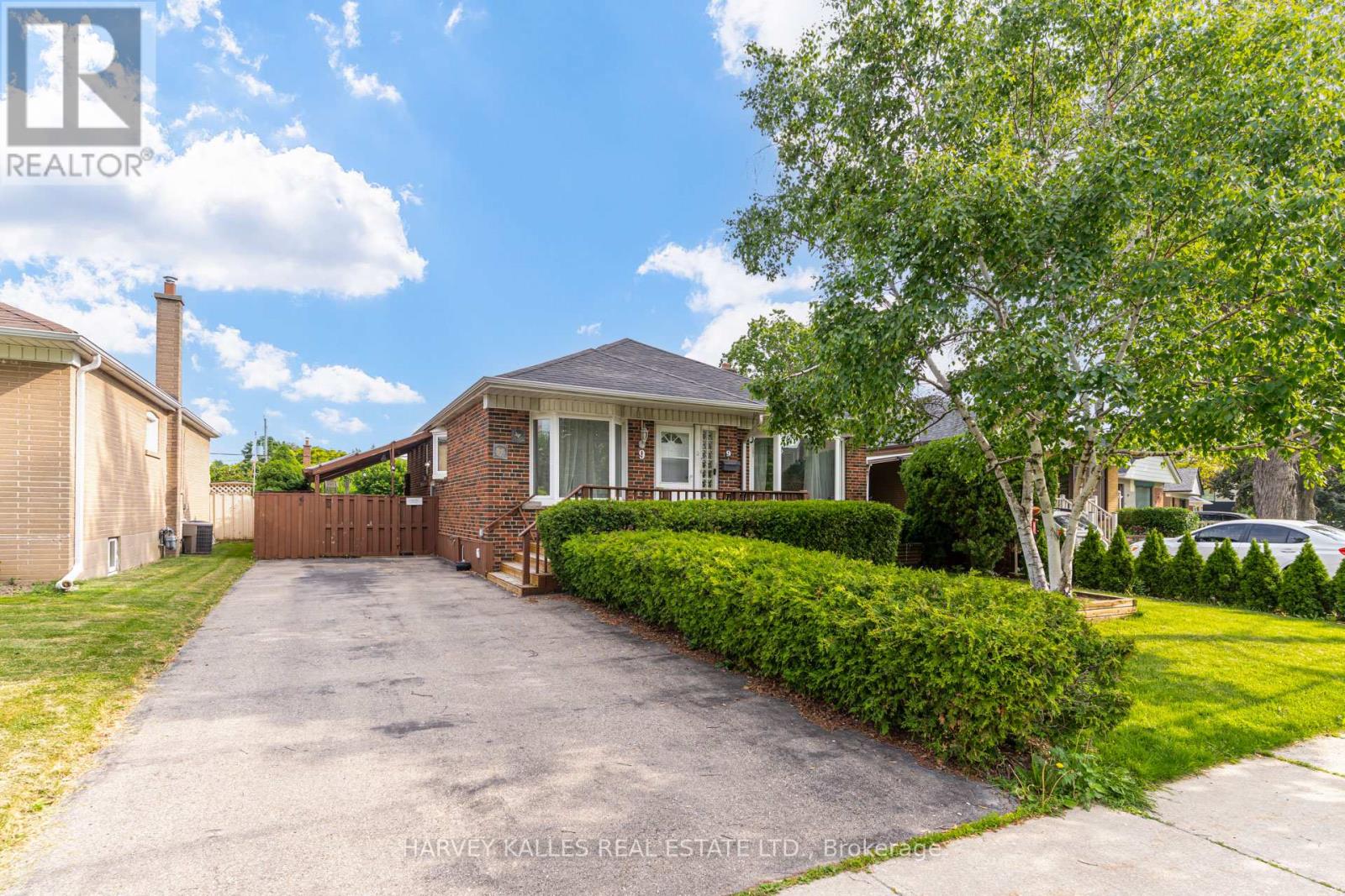 Single-storey brick house with a broad driveway, wooden gate, and trimmed front hedges.