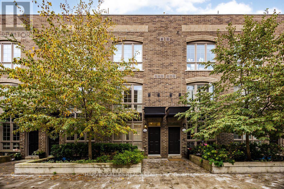 Brick townhouse façade with paired black entrances, arched windows, and leafy trees.