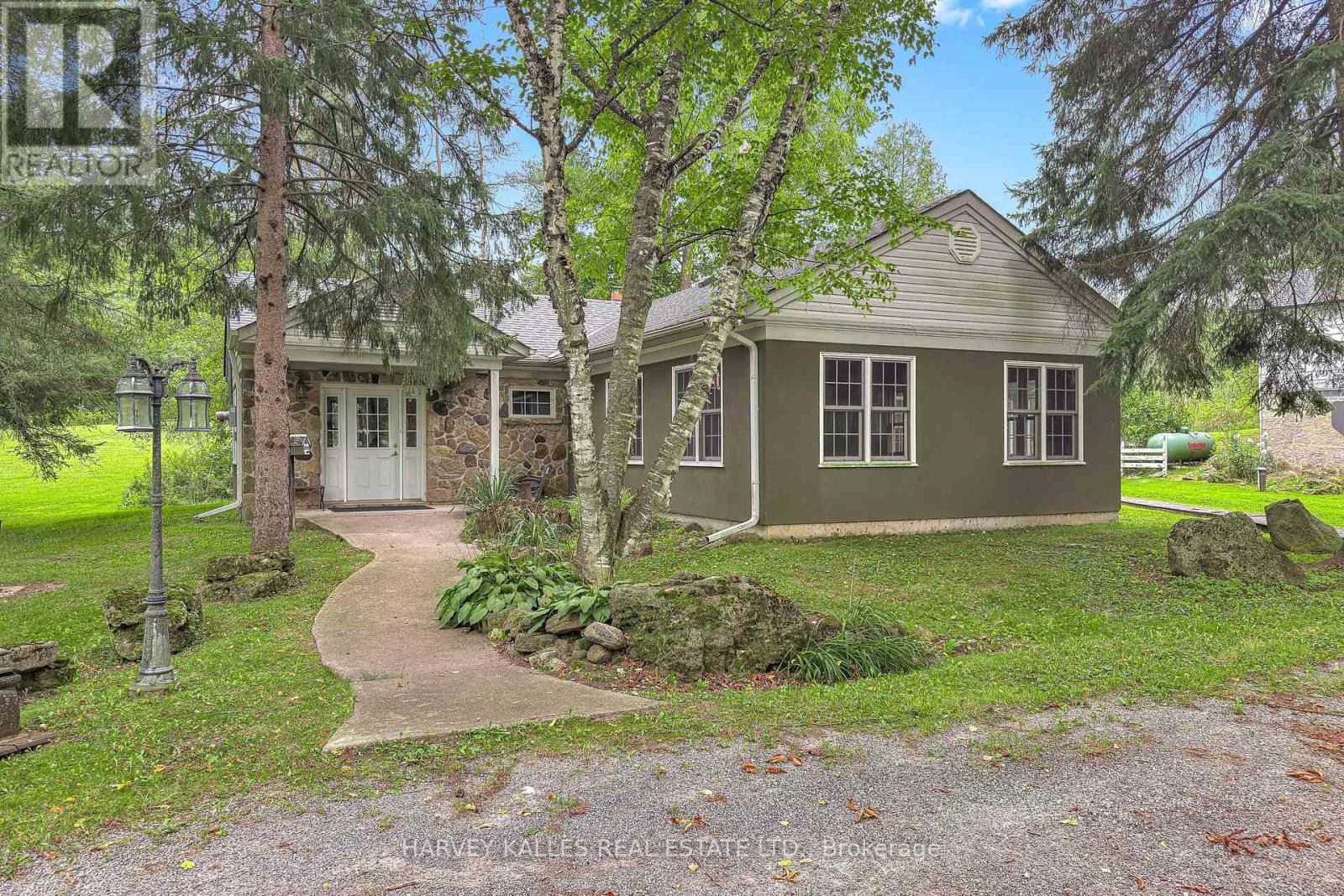 Single-storey house with a stone entry, framed by mature trees and a curved front walkway.