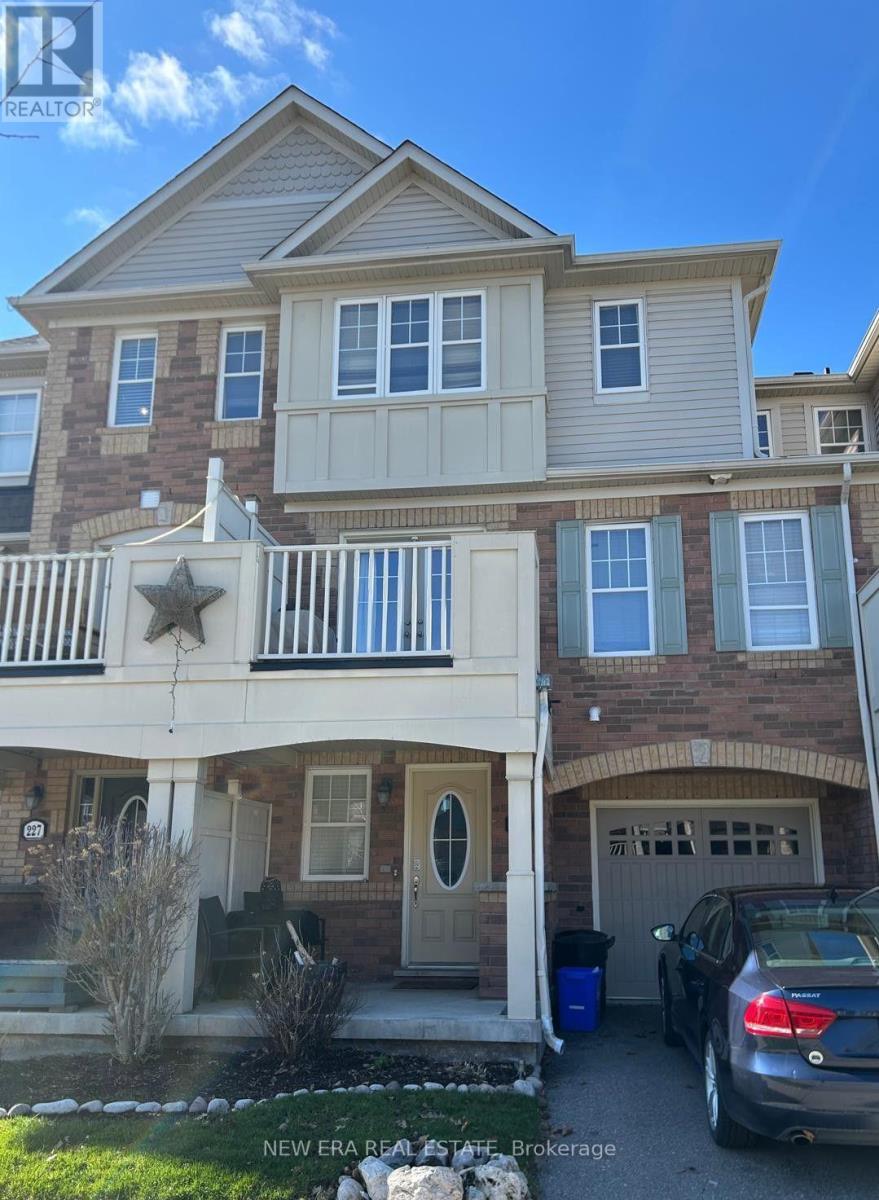 Brick townhouse with a covered balcony, attached garage, and car parked in the driveway.