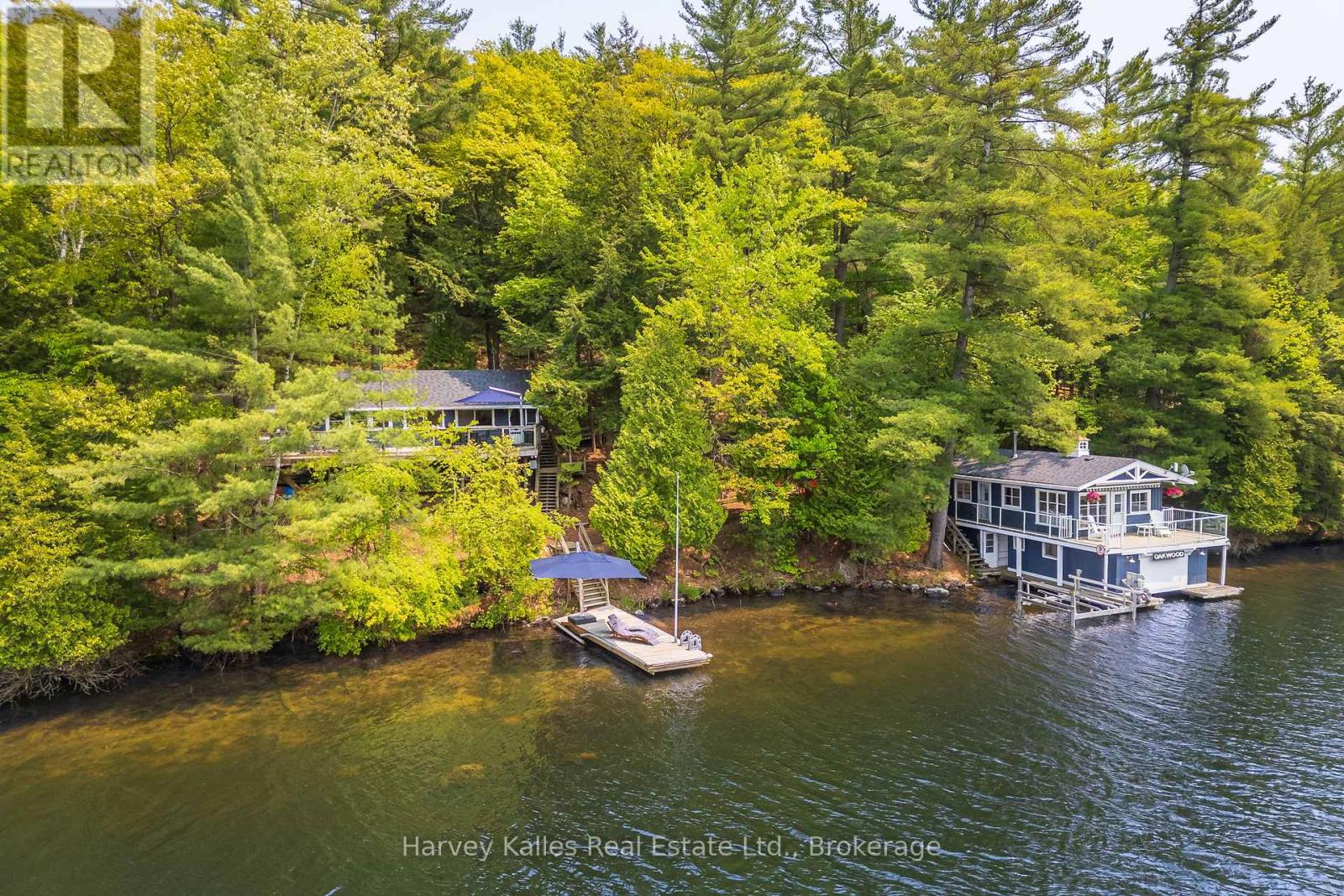 Two wooded waterfront homes along a lake, with a dock and broad deck.