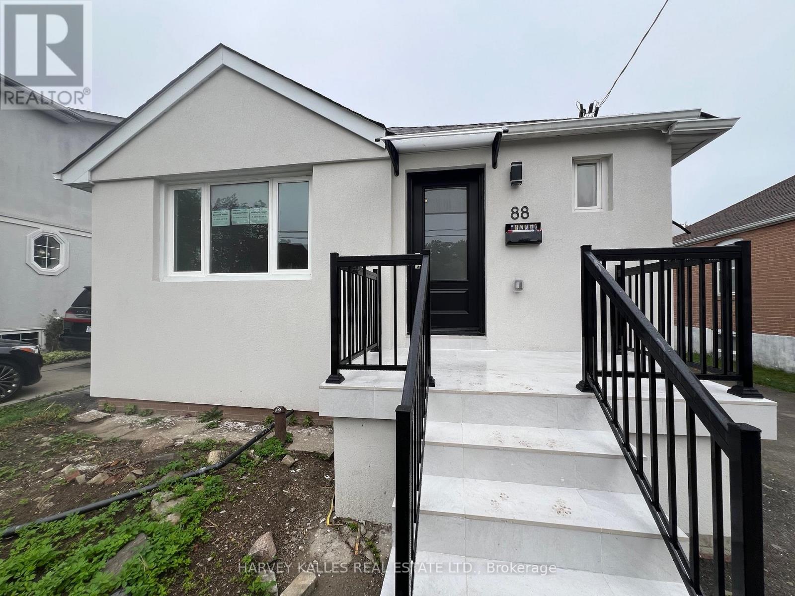 White stucco house with black railings framing a broad tiled staircase to the front door.
