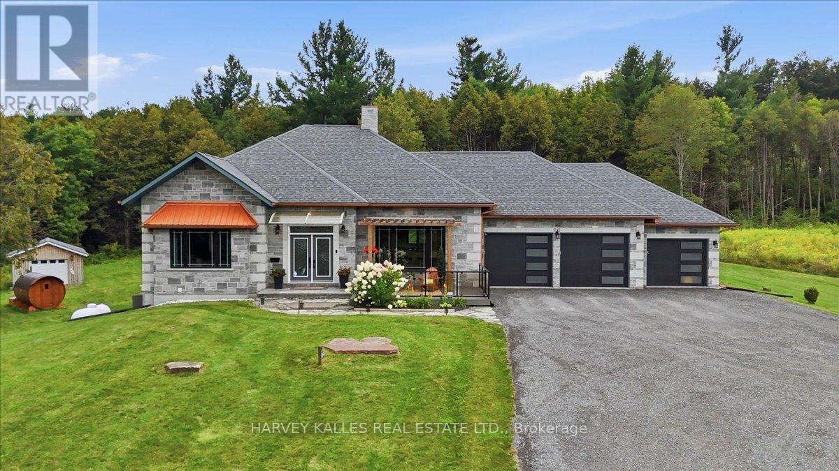 Stone ranch house with a three-car garage, broad driveway, and wooded backdrop.