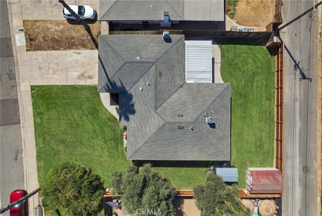 Aerial view of a gray-shingled house surrounded by a large lawn and fenced yard.