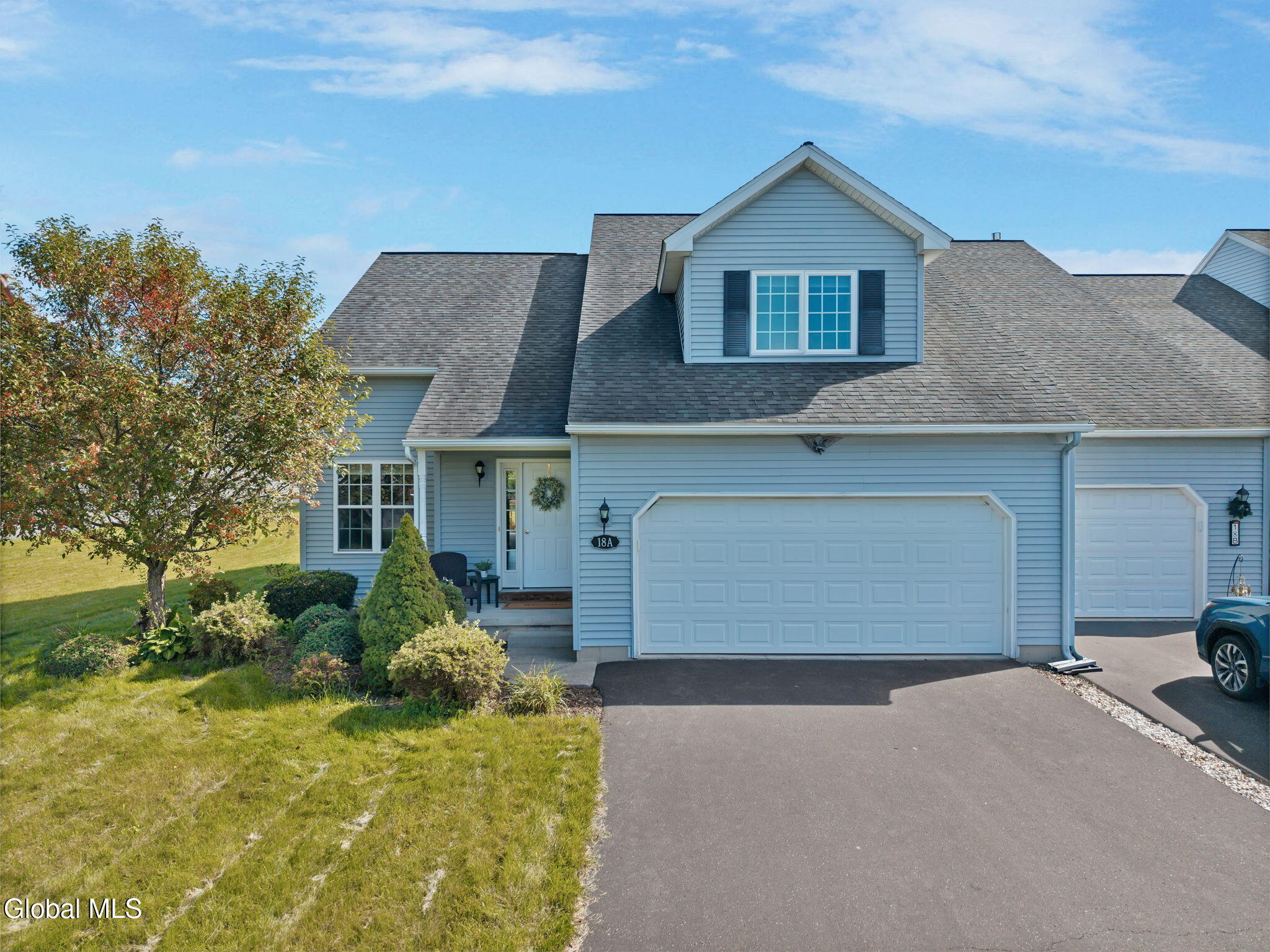 Light blue two-story home with a double garage, landscaped yard, and 18A address plaque.