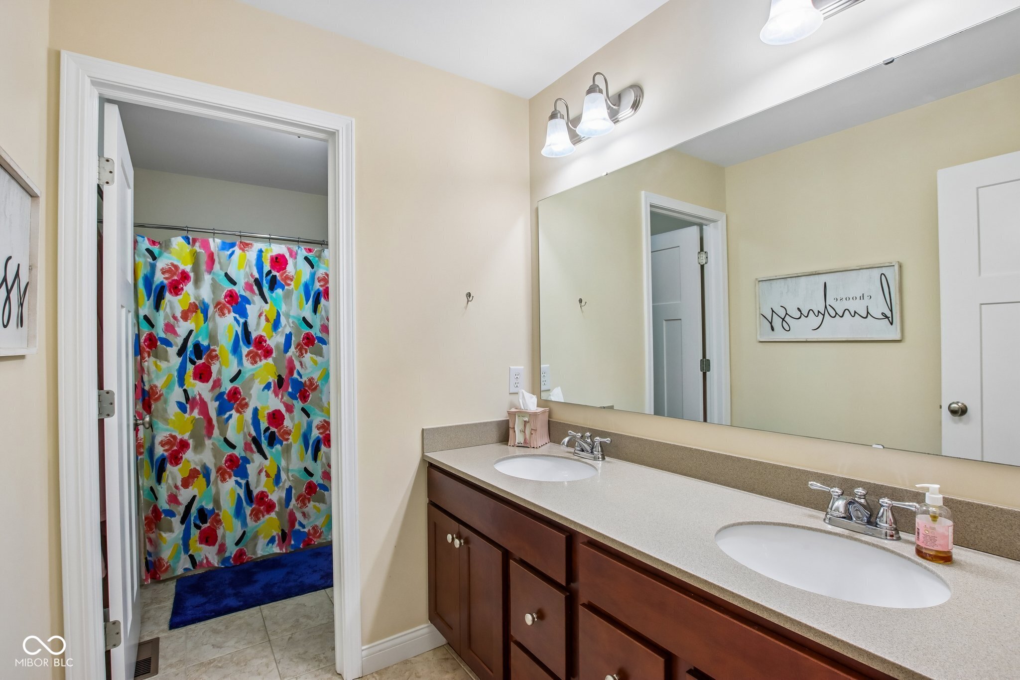Bathroom with a double-sink dark wood vanity and a colorful floral shower curtain.