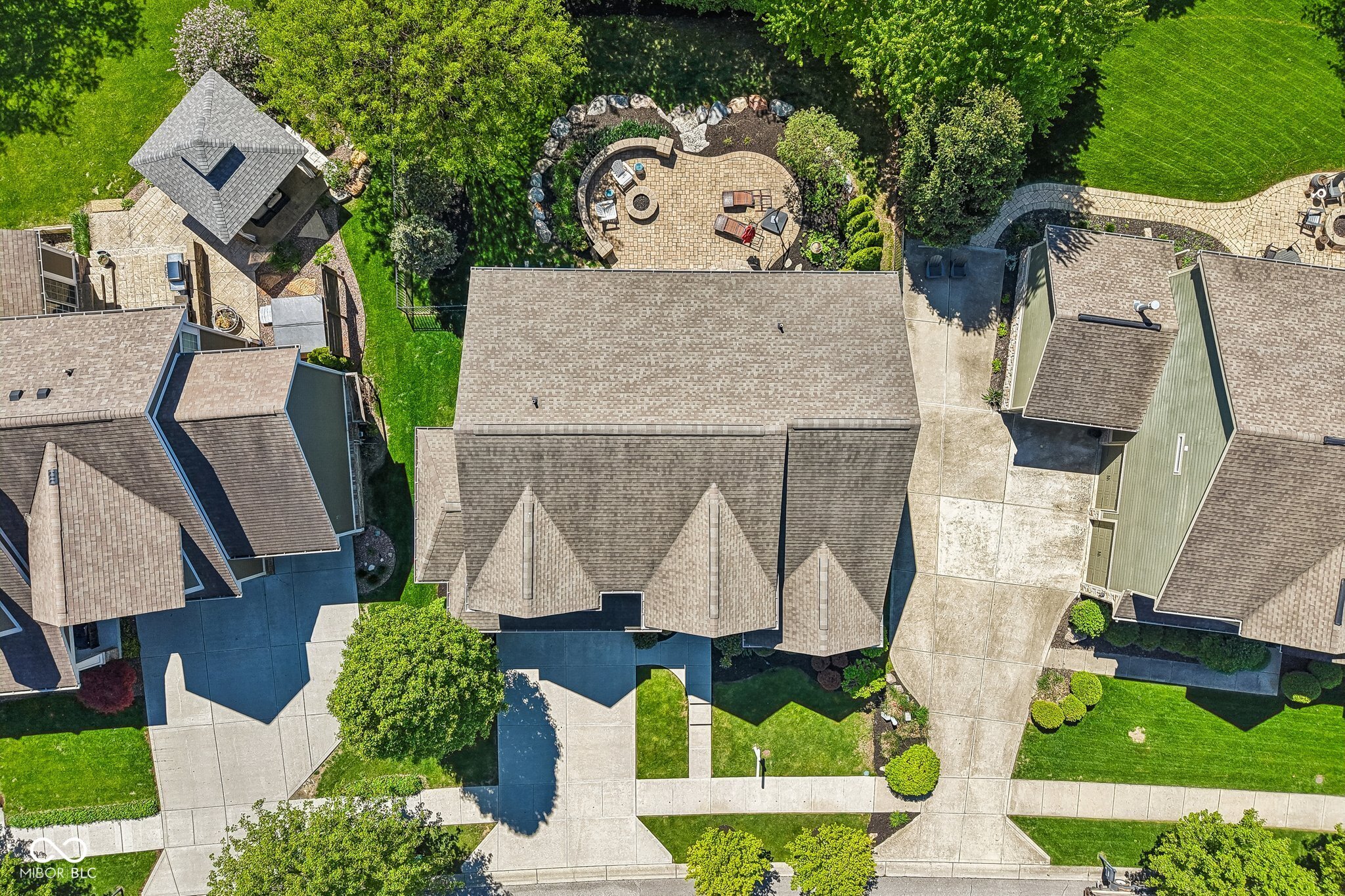 Home with a landscaped stone patio and seating, viewed from directly above.