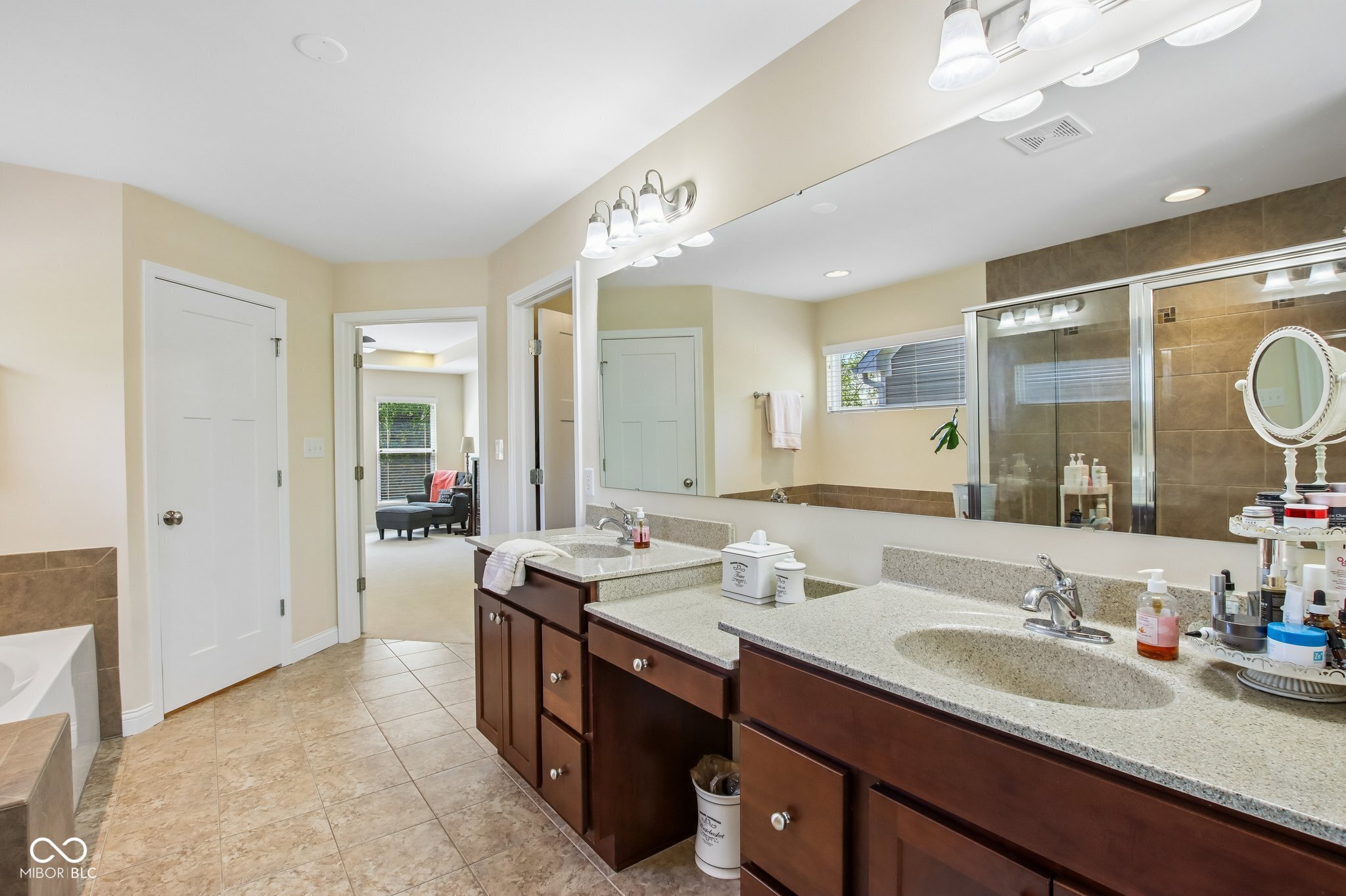 Bathroom with a long double-sink vanity, large mirror, and tiled glass shower.