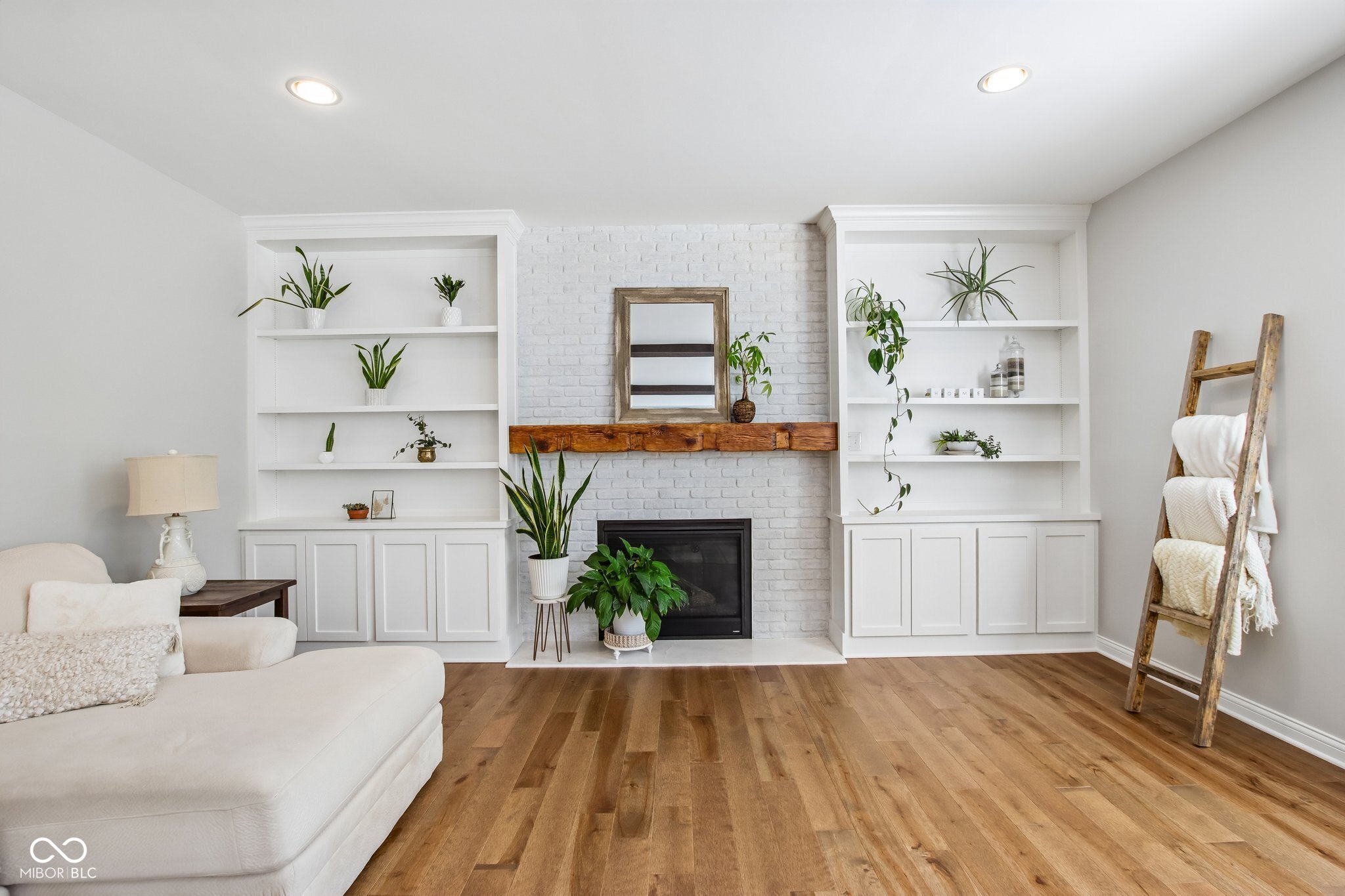 Living room with a white brick fireplace, built-in shelves, and warm hardwood floors.