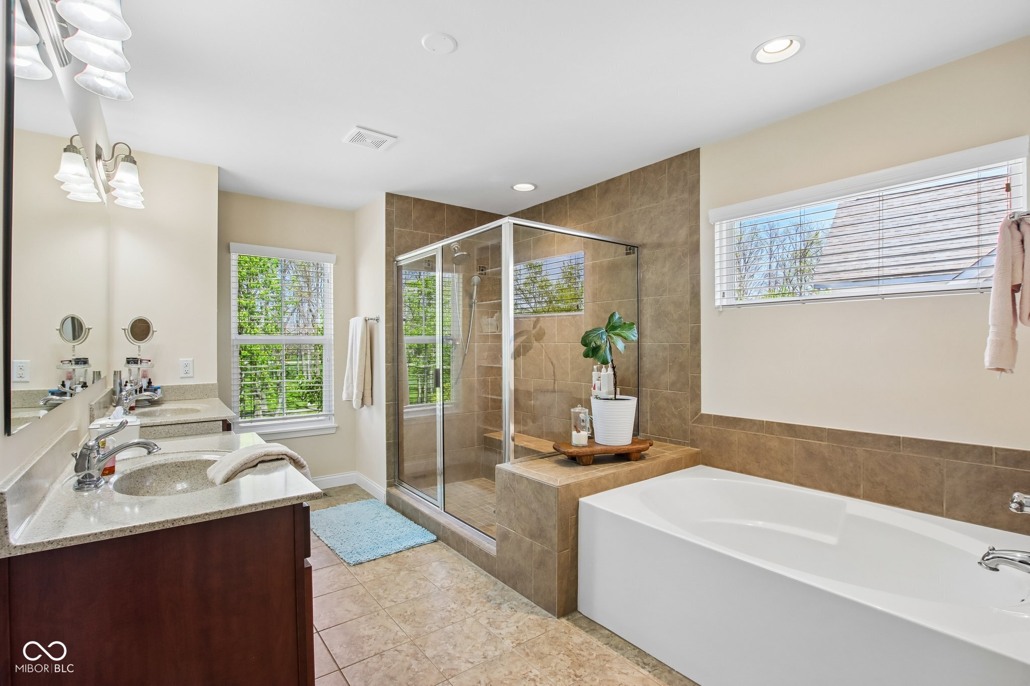 Primary bathroom with a double vanity, glass shower, and large soaking tub.
