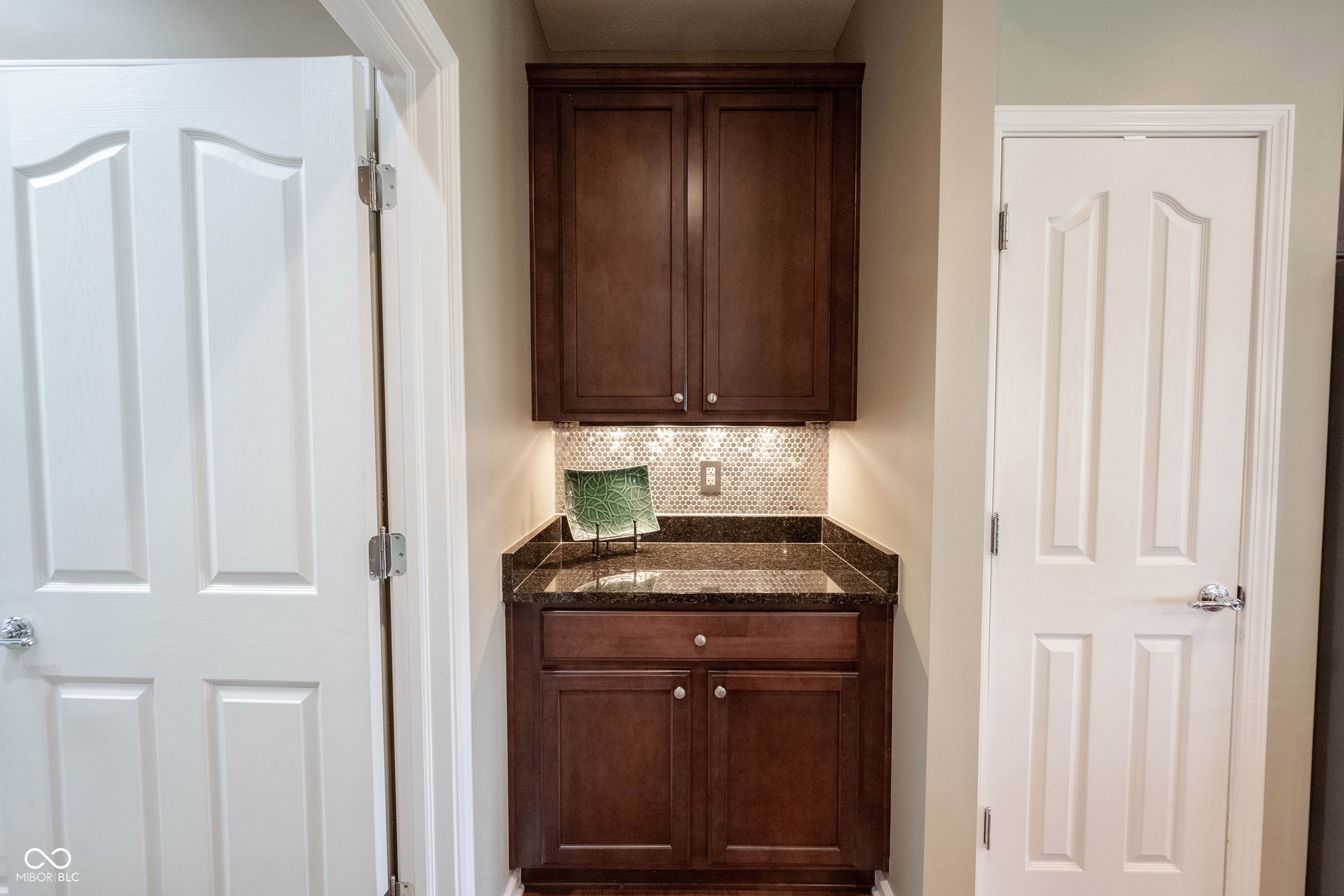 Built-in bar nook with dark wood cabinets, a stone counter, and a tiled backsplash.