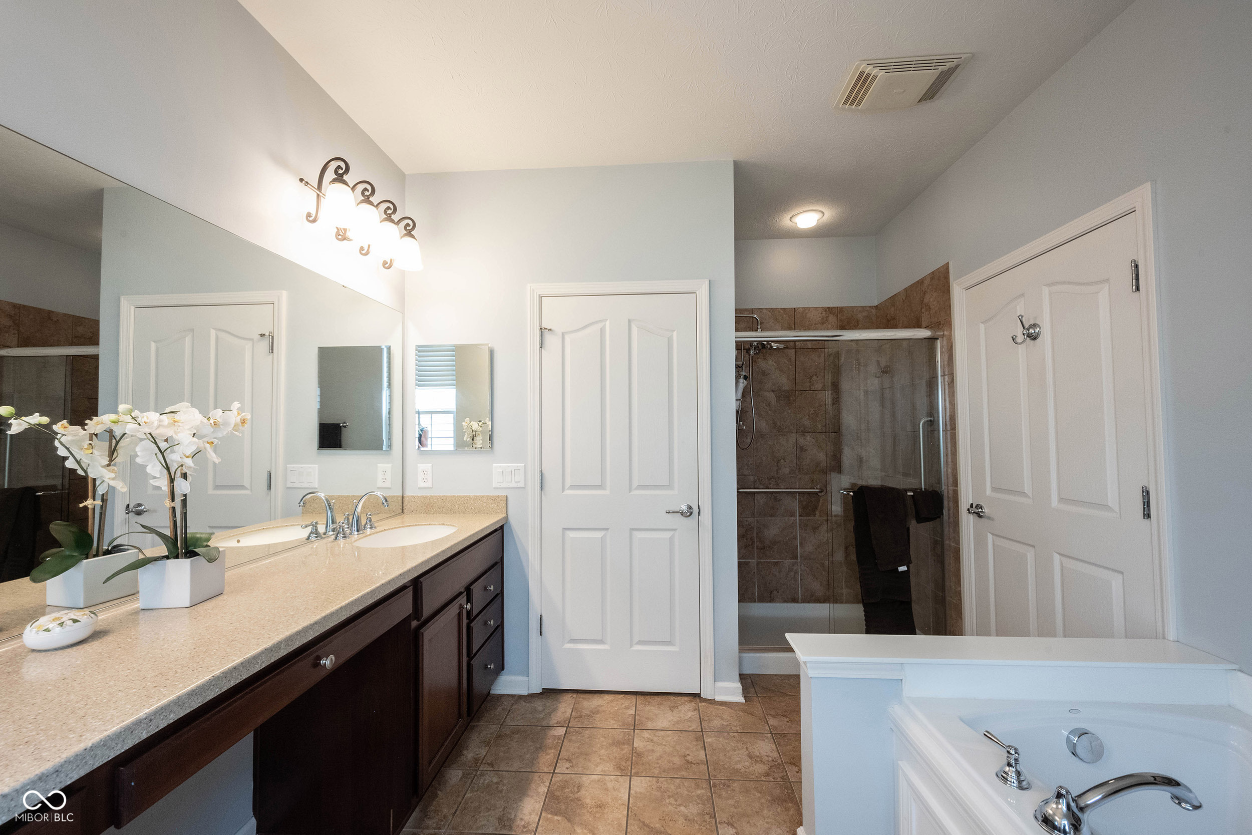 Bathroom with a double vanity, tiled shower, and built-in soaking tub.