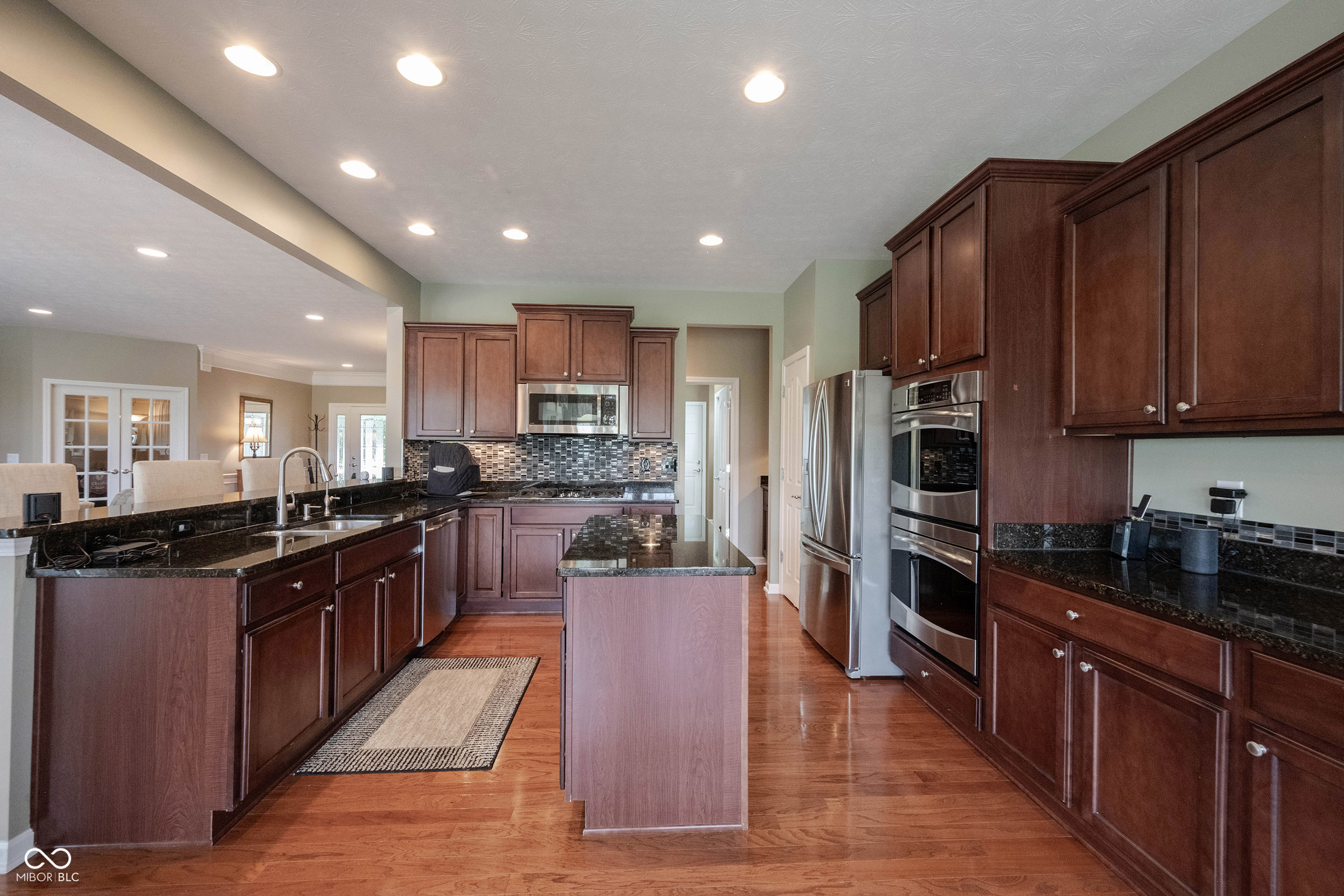 Spacious kitchen with dark cherry cabinets, granite counters, a central island, and stainless steel appliances.
