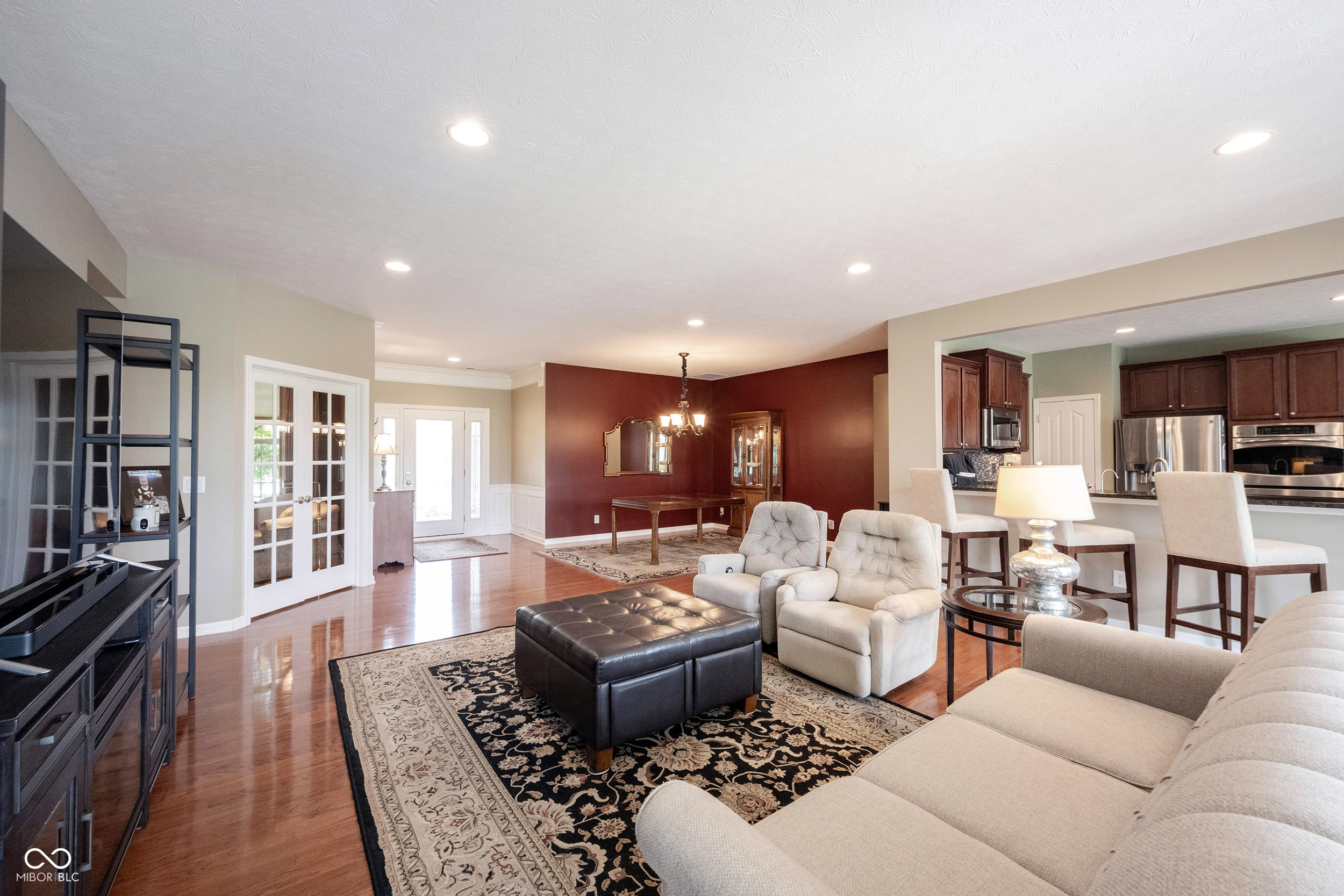 Open-plan living room with hardwood floors, patterned rug, and adjoining dining area and kitchen.