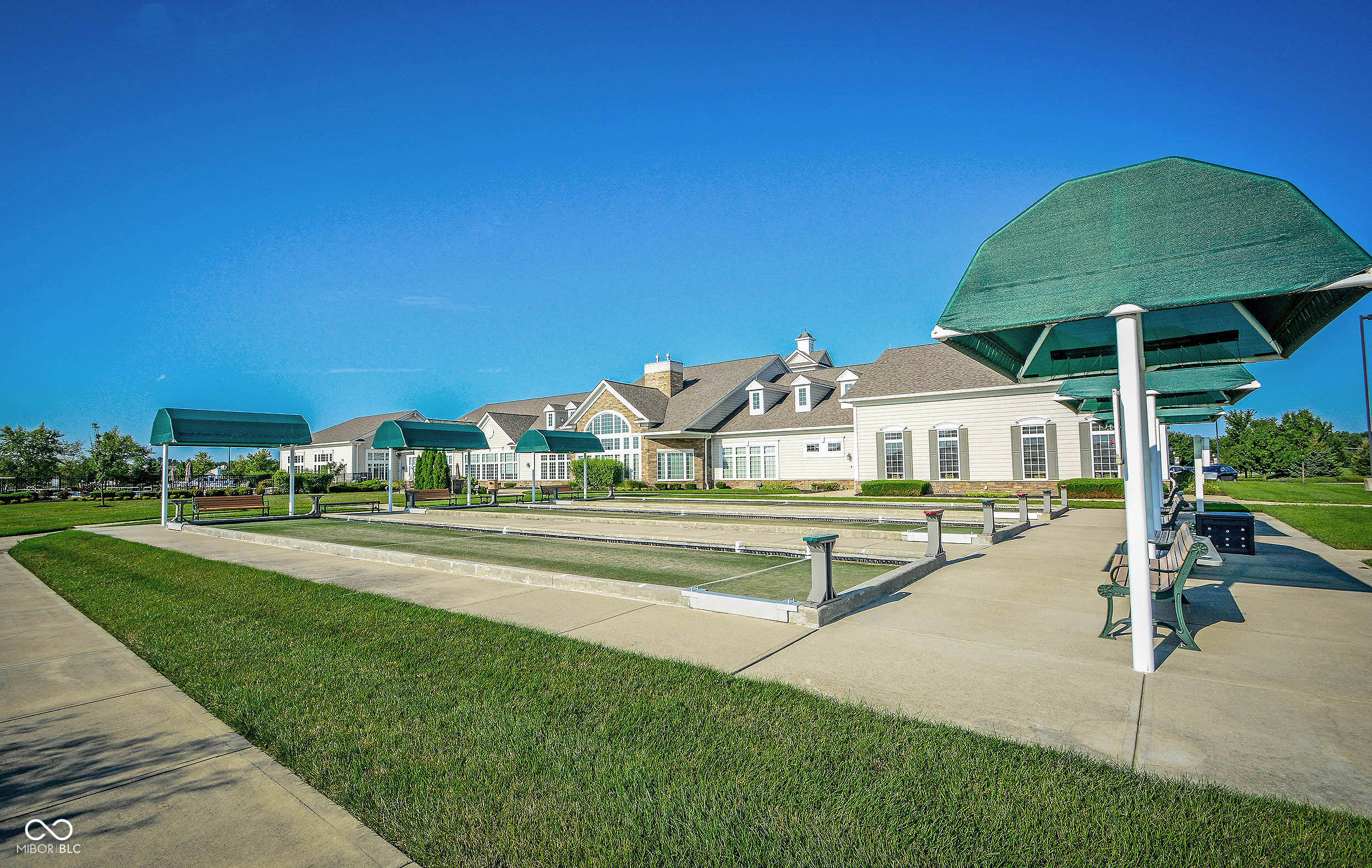 Community clubhouse and bocce courts with green shade canopies and benches.