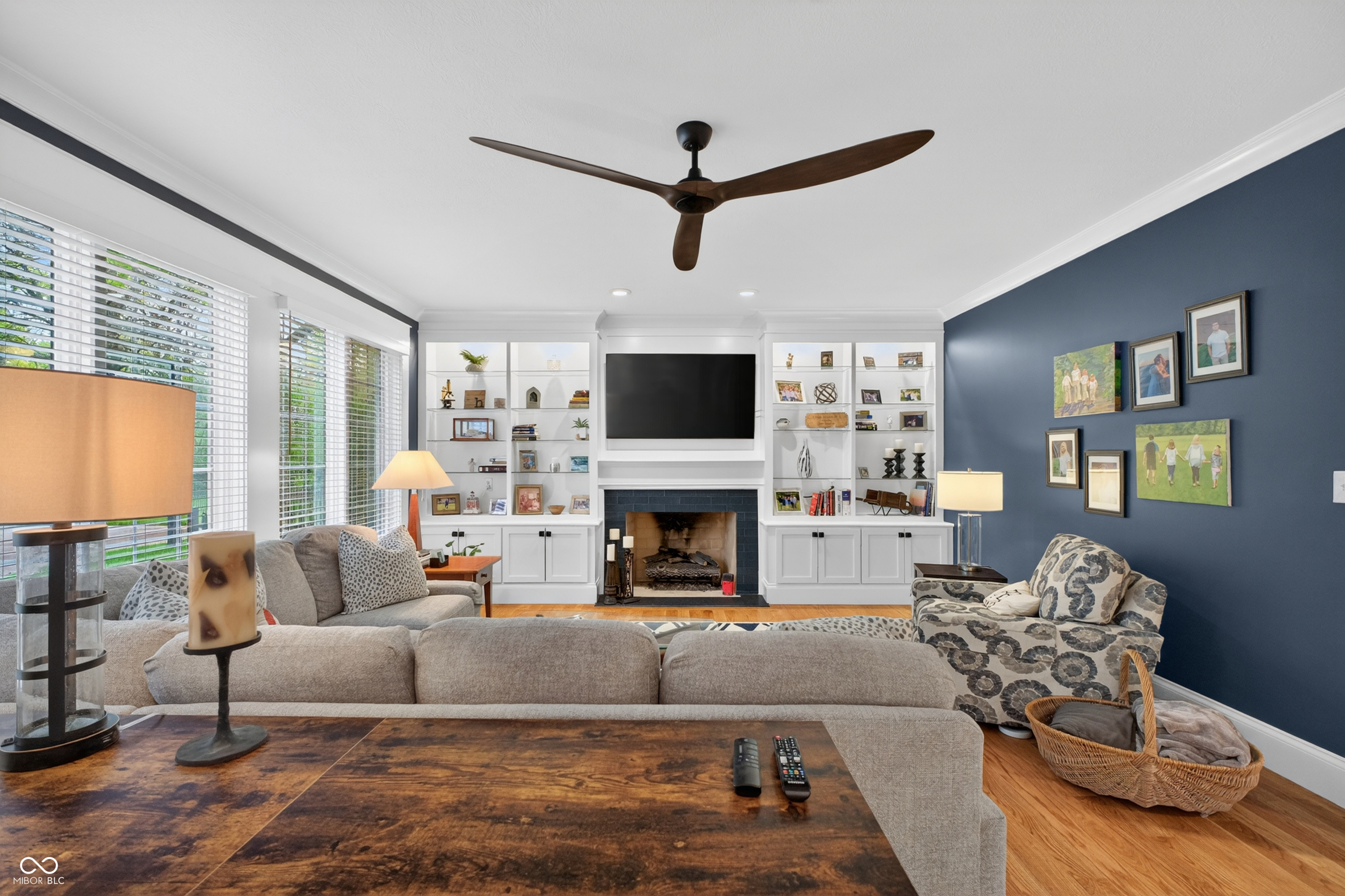 Living room with white fireplace built-ins, a gray sectional, and a dark blue accent wall.