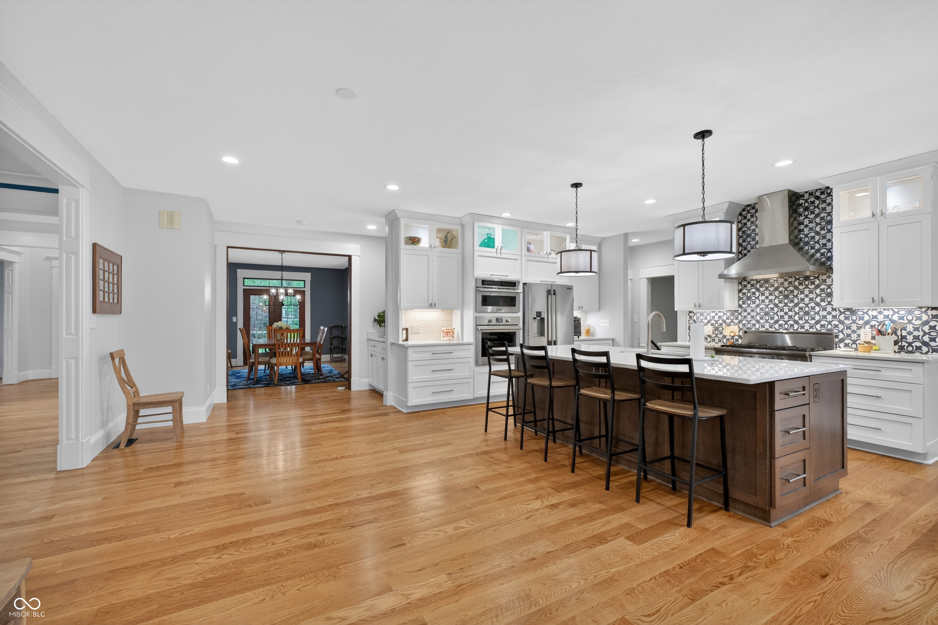 Kitchen with a large dark-wood island, white cabinets, patterned backsplash, and adjoining dining room.