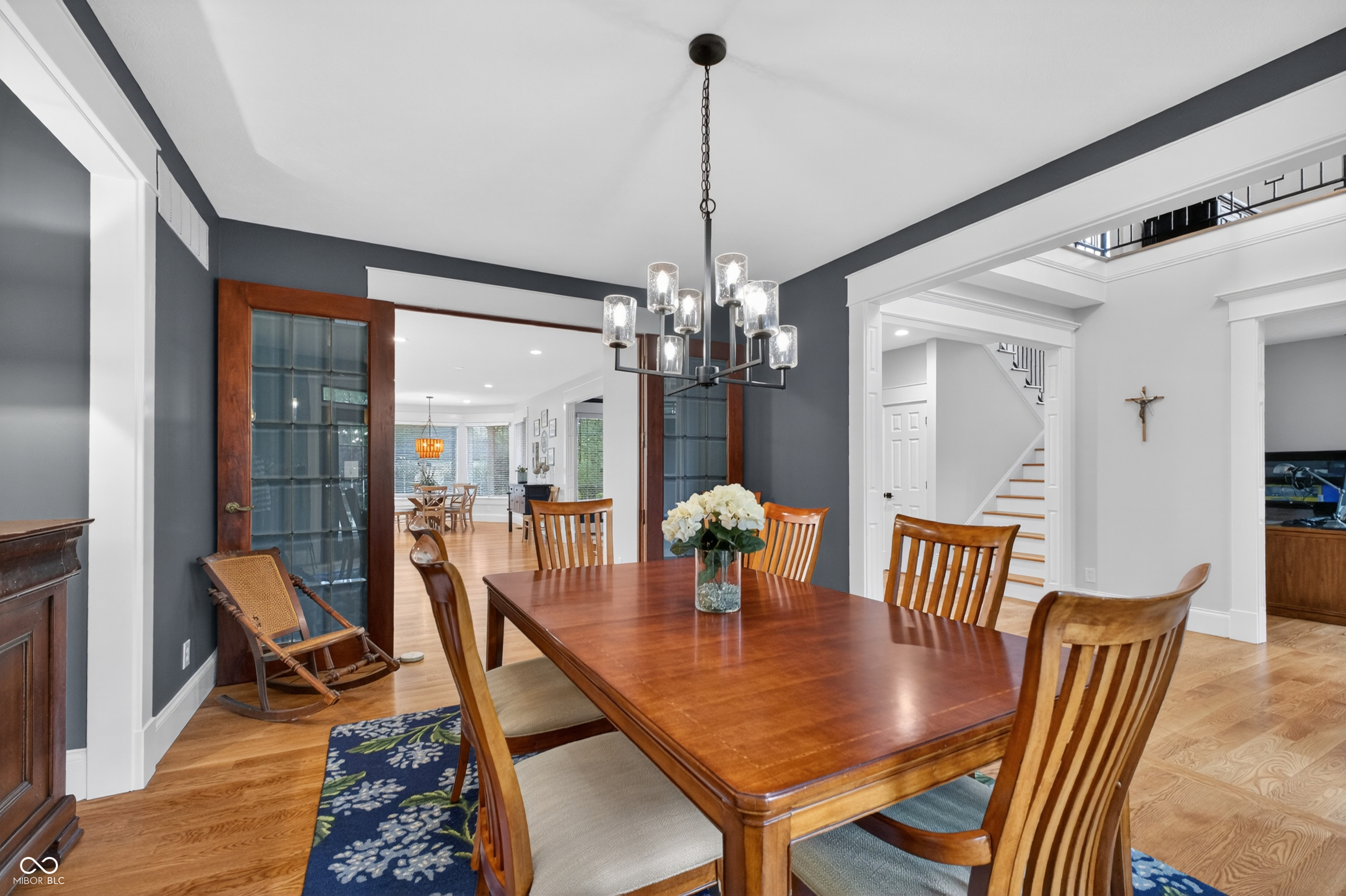 Dining room with a polished wood table, glass-paneled doors, and a chandelier.