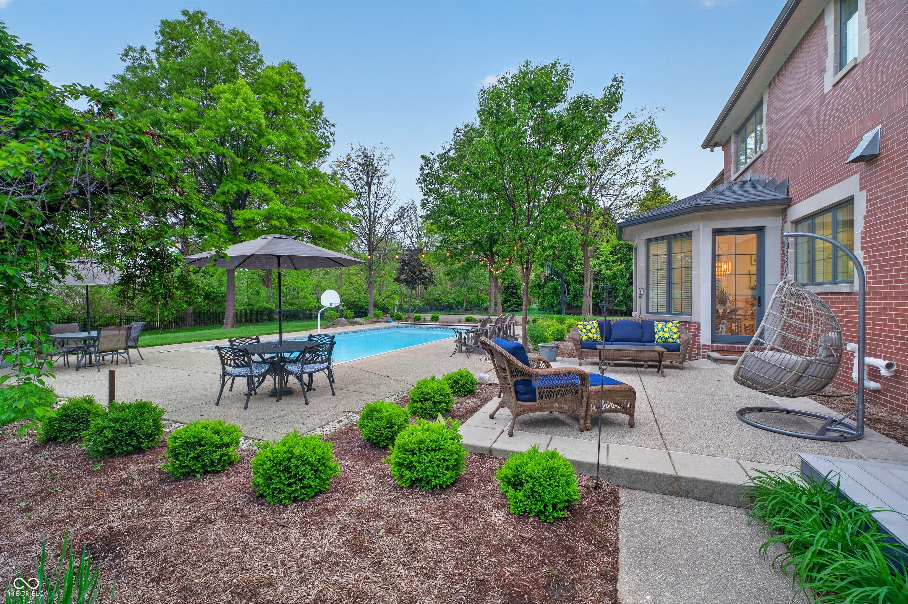 Backyard pool and patio with outdoor dining, lounge seating, and a hanging egg chair.
