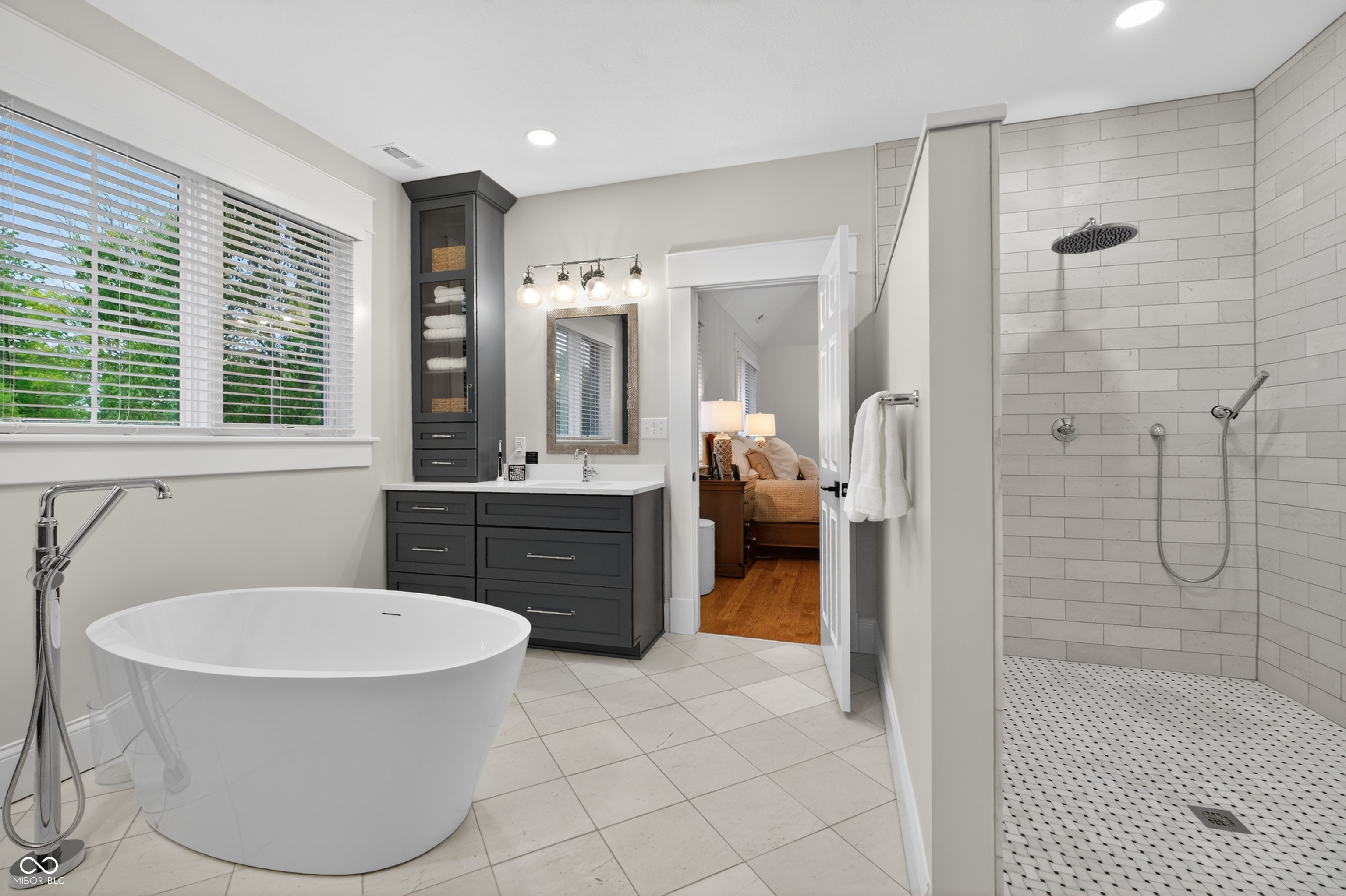 Bathroom with a freestanding soaking tub, dark vanity, and spacious tiled walk-in shower.