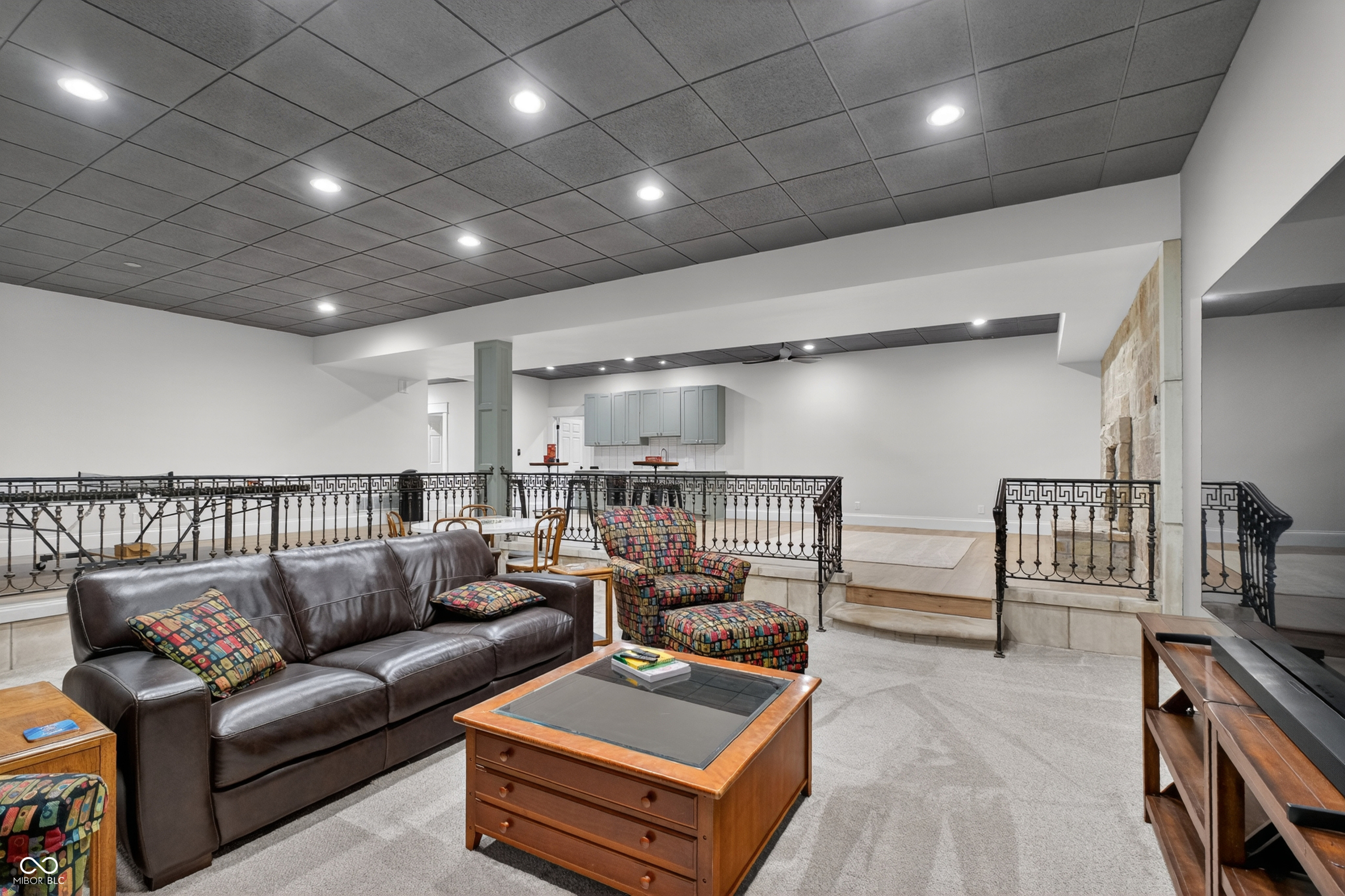 Furnished living area with a leather sofa, colorful armchair, and decorative metal railings.