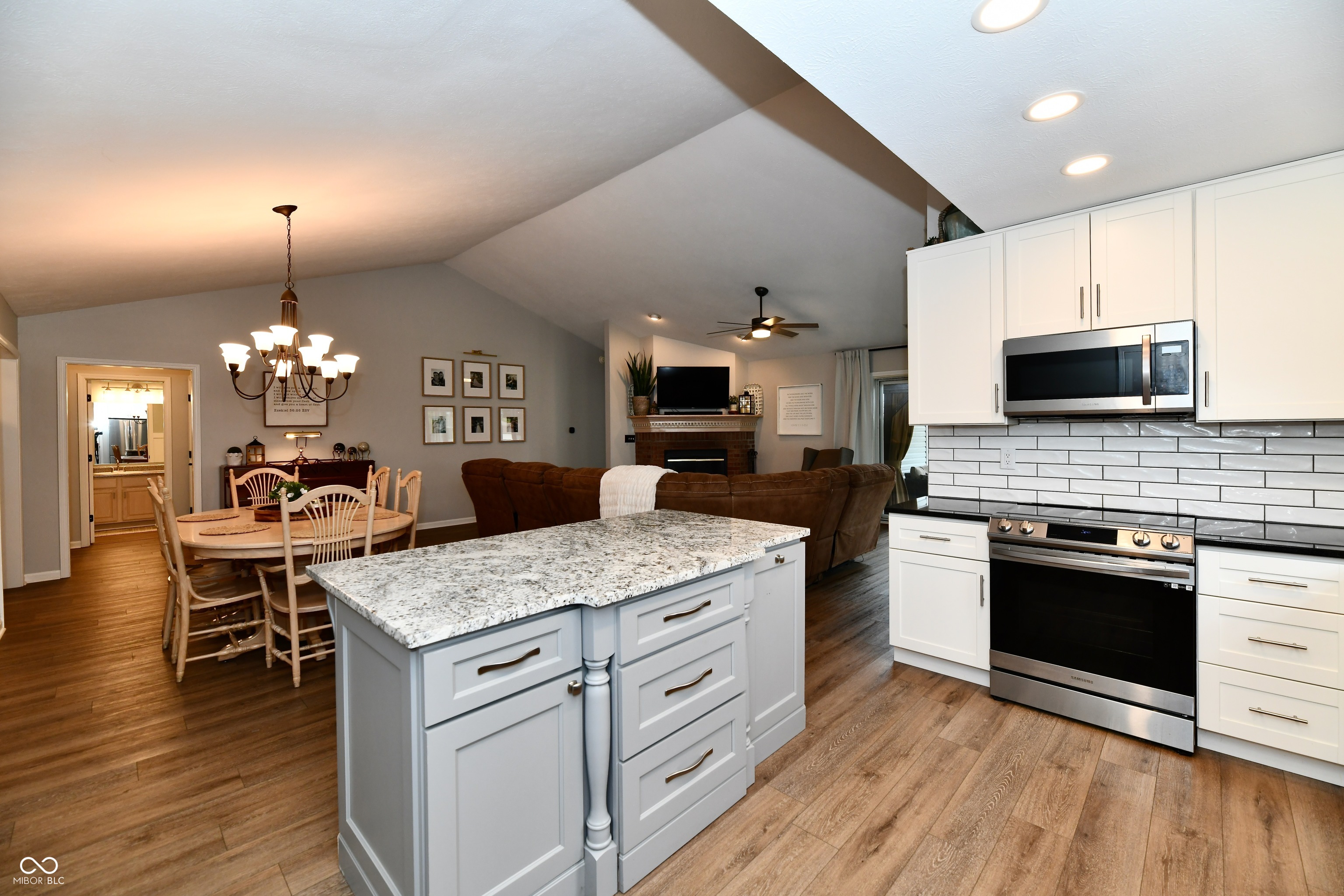 Open-plan kitchen with a granite island, white cabinets, and dining and living areas beyond.