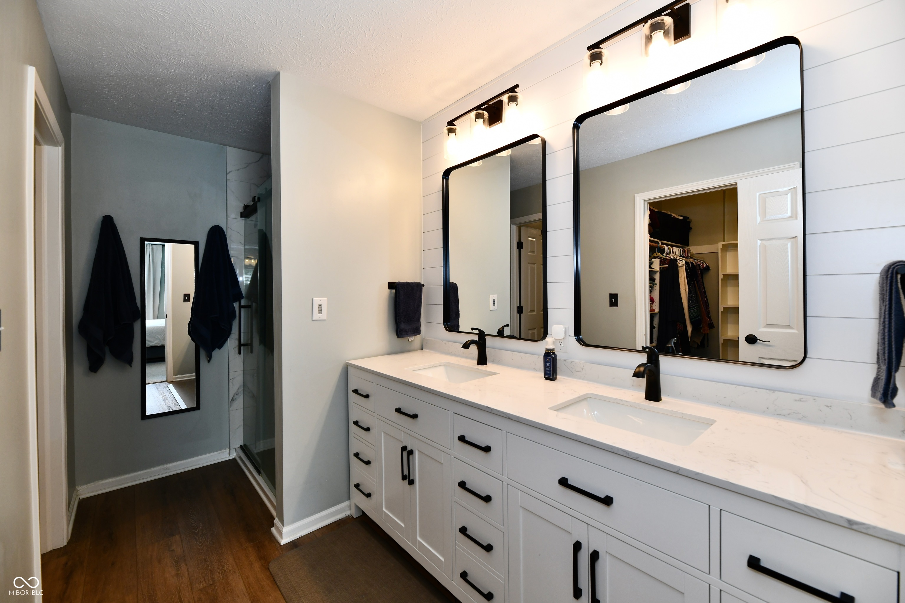 Bathroom with a long double vanity, black-framed mirrors, and a glass-enclosed shower.