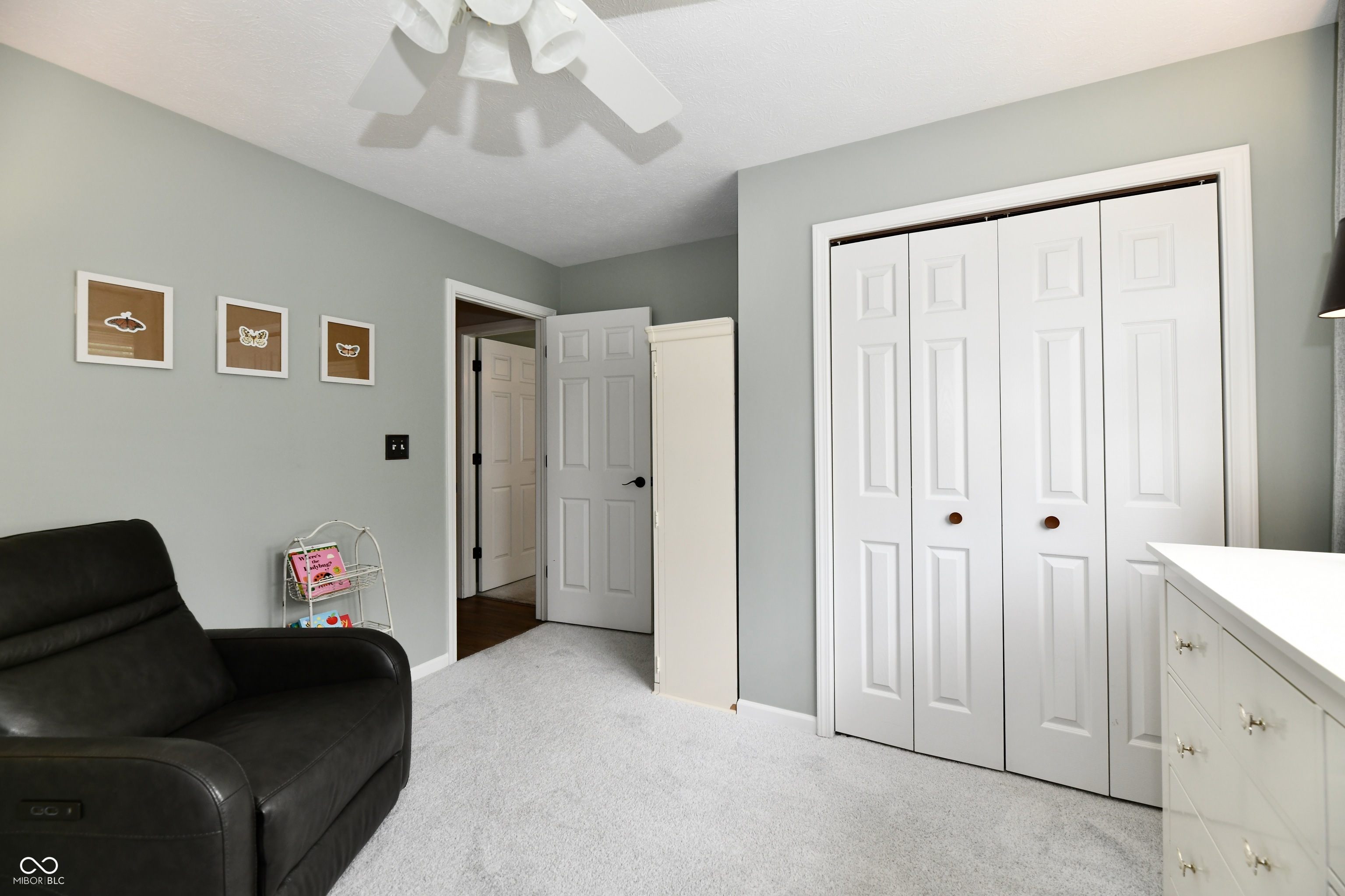Furnished bedroom with white closet doors, gray carpet, and a black recliner.