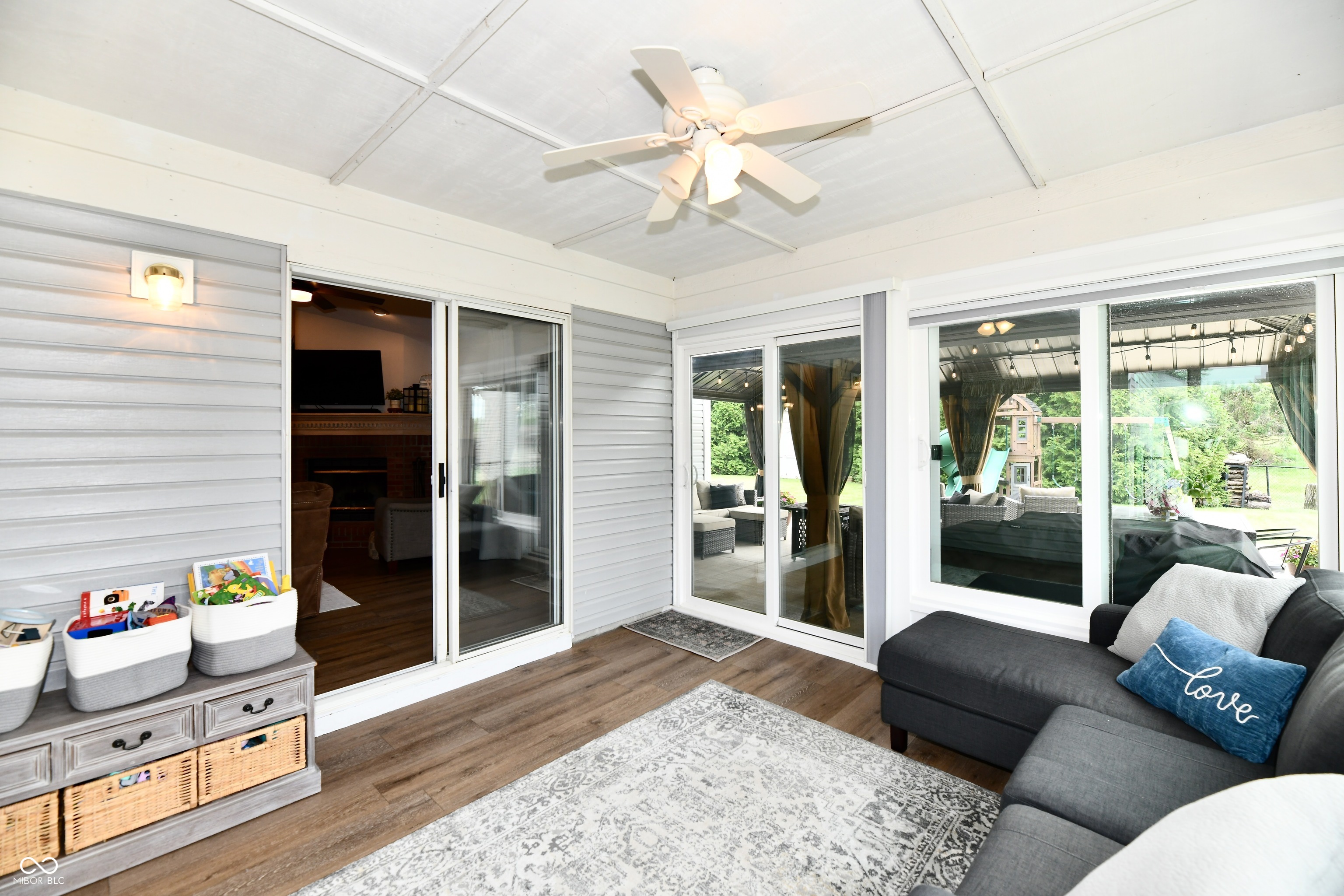 Furnished sunroom with a gray sectional, ceiling fan, and glass doors opening onto a covered patio.