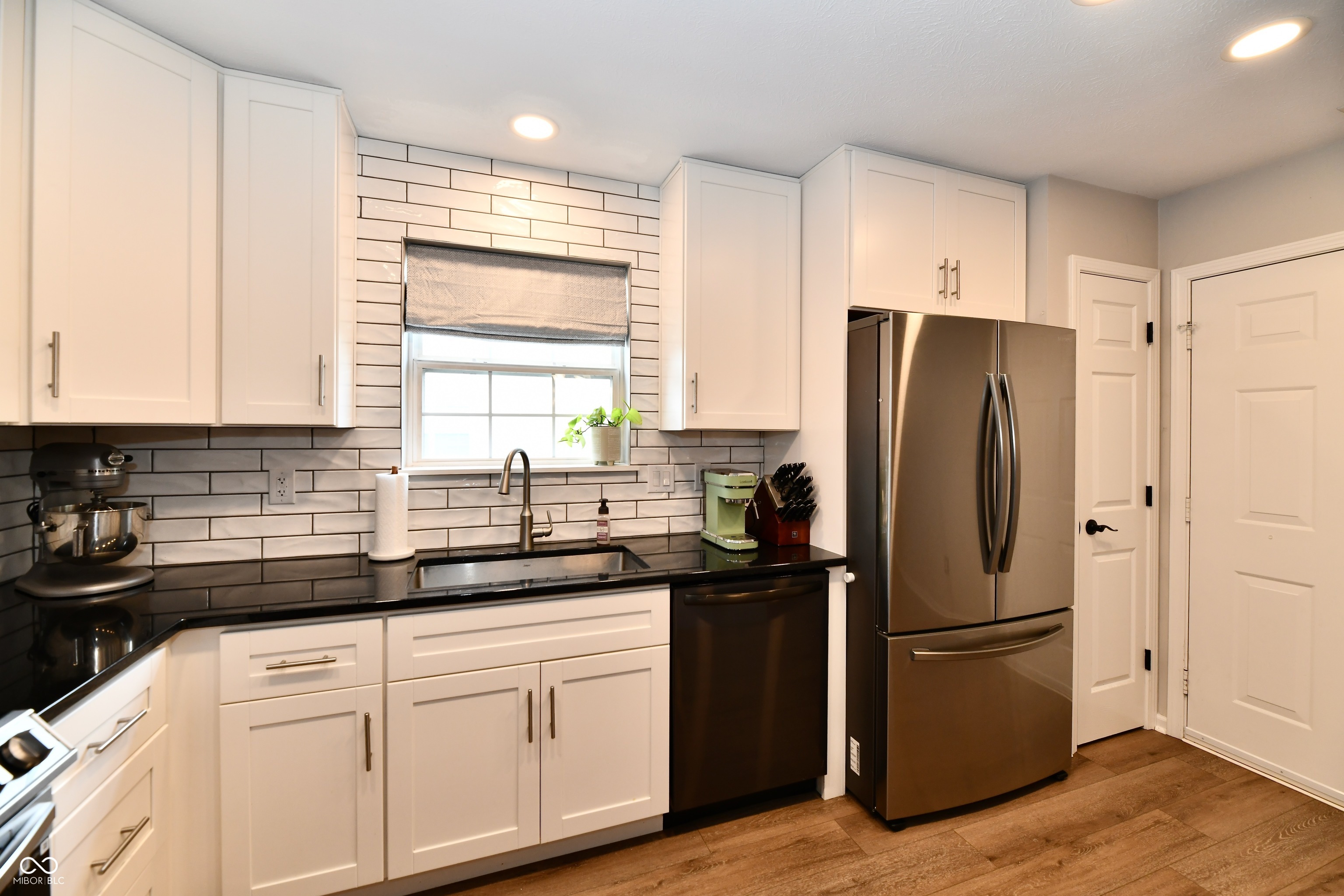 Kitchen with white shaker cabinets, dark countertops, subway-tile backsplash, and stainless-steel appliances.