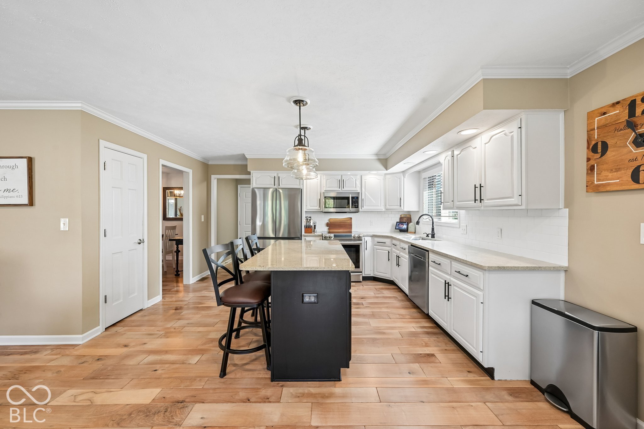 Kitchen with white cabinets, stainless steel appliances, and a large island with bar stools.
