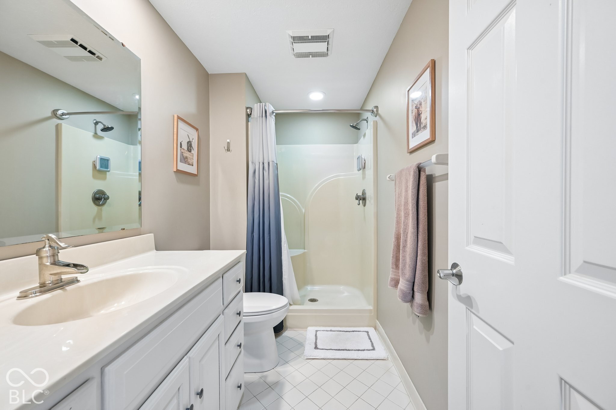 Bathroom with a long white vanity, large mirror, and glass-enclosed shower.