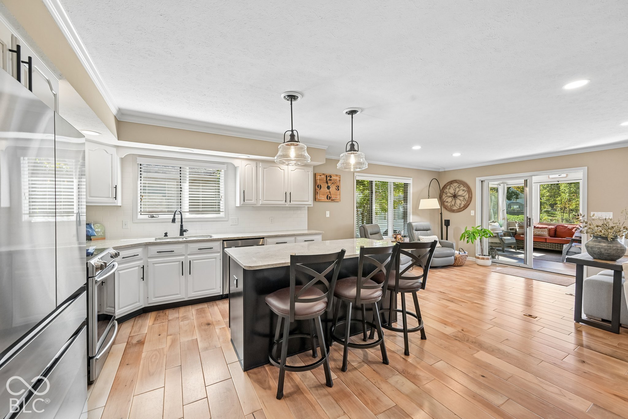 Open kitchen with white cabinets, a black island and bar stools, and glass doors to a patio.