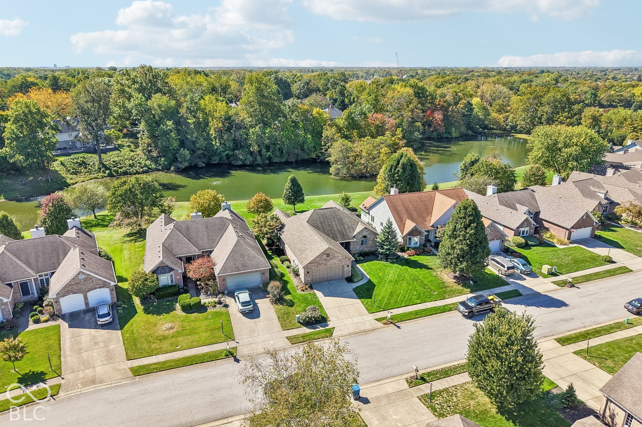 Aerial view of neighborhood homes beside a tree-lined pond.