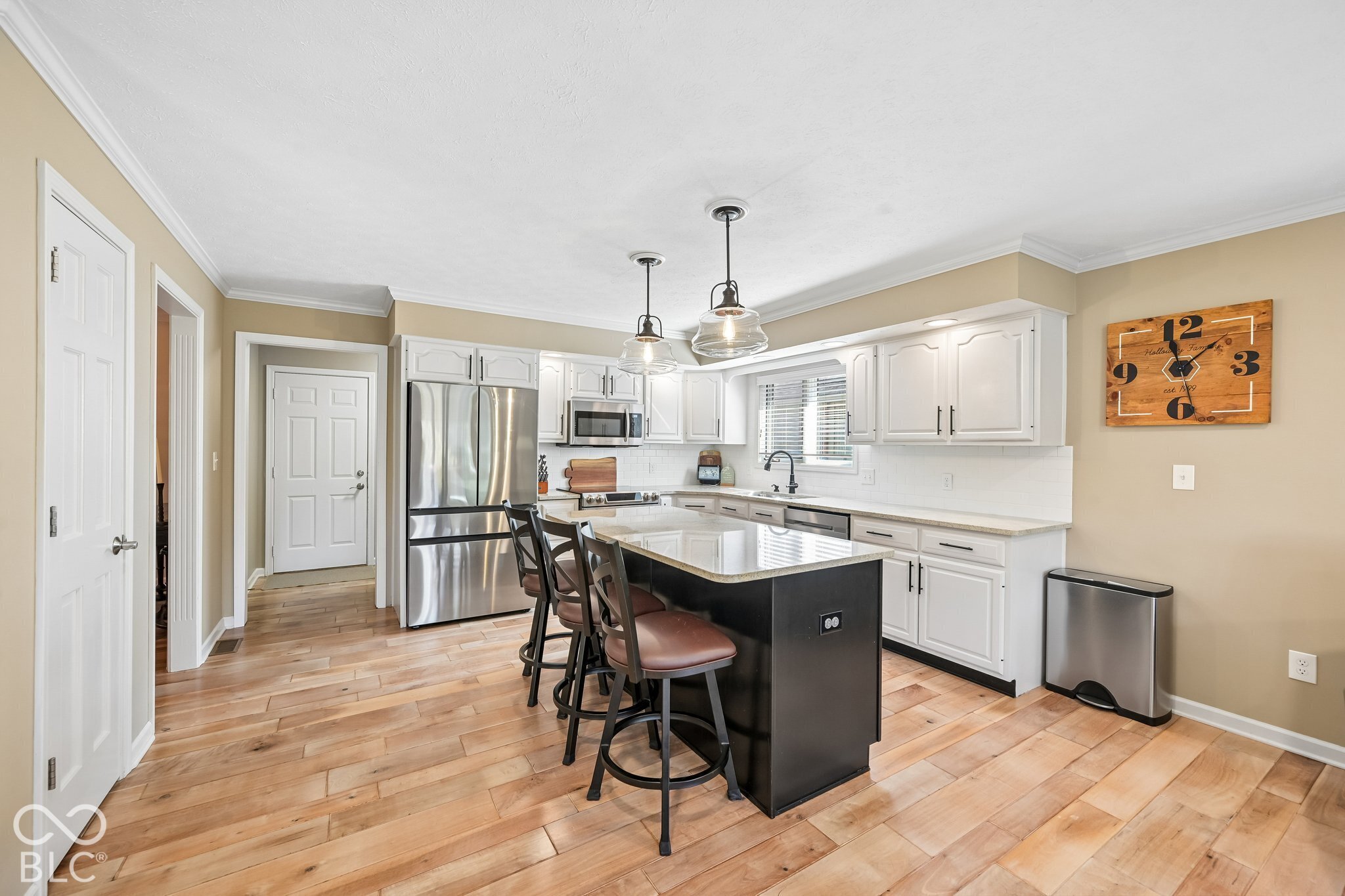Kitchen with white cabinets, stainless steel appliances, and a black island with bar stools.