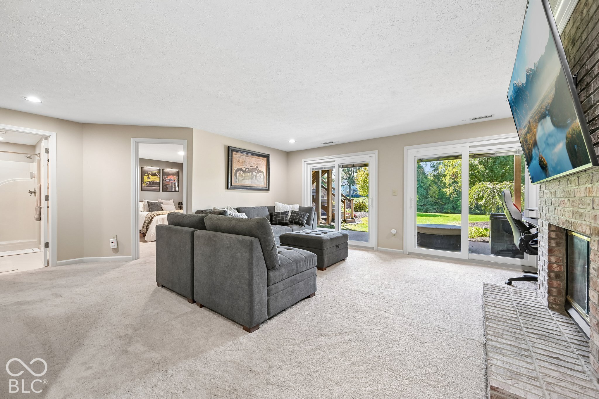 Living room with a gray sectional, brick fireplace, and sliding glass doors overlooking the backyard.