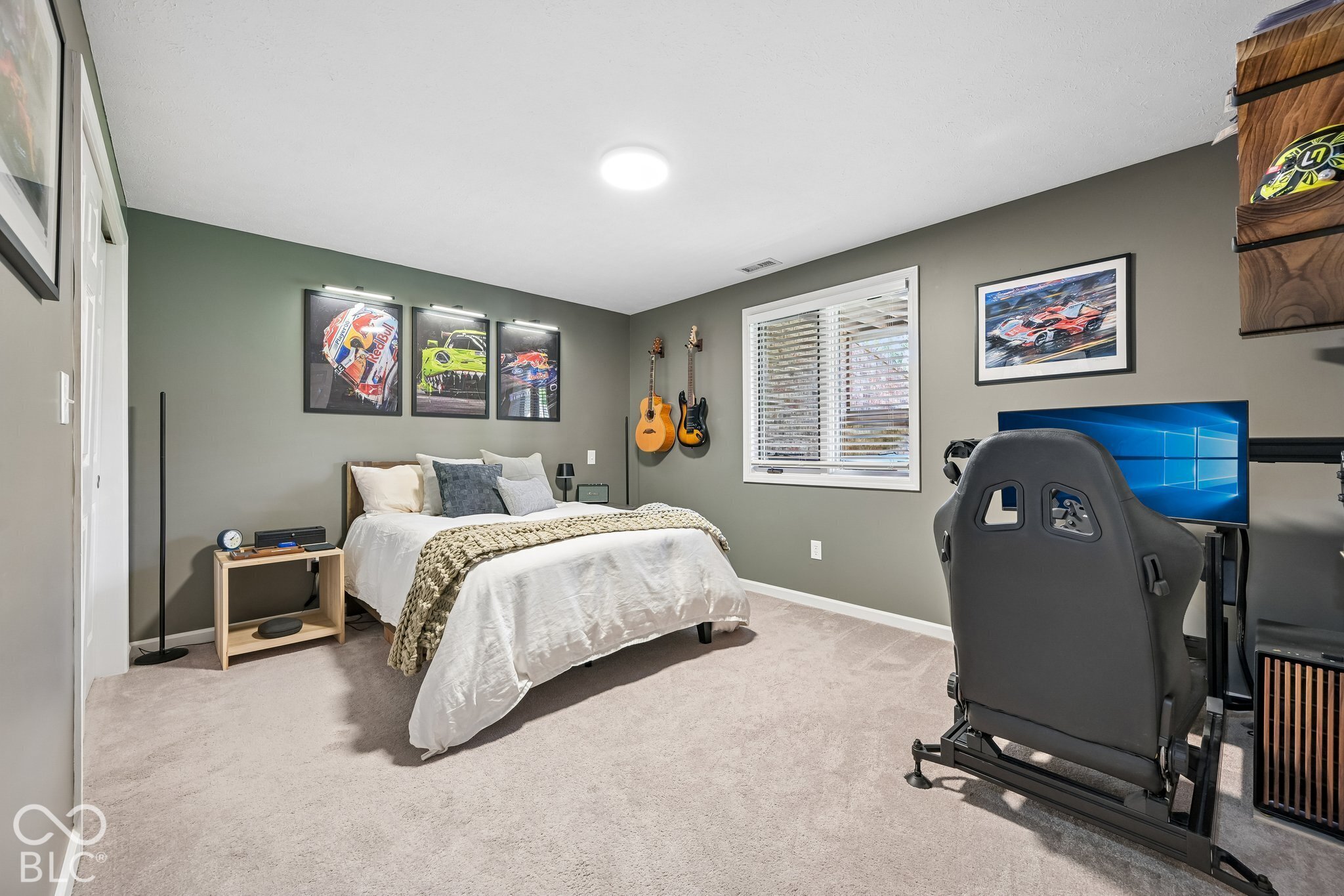 Bedroom with a white bed, guitars, motorsports artwork, and a racing simulator.