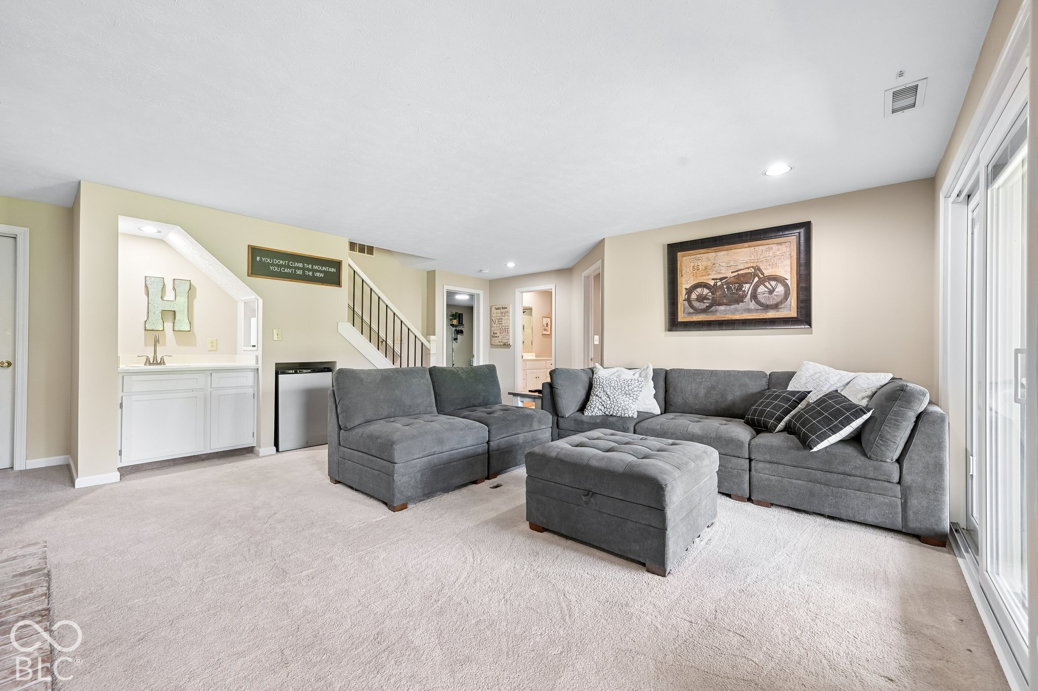 Furnished living room with a gray sectional and ottoman beside sliding glass doors.