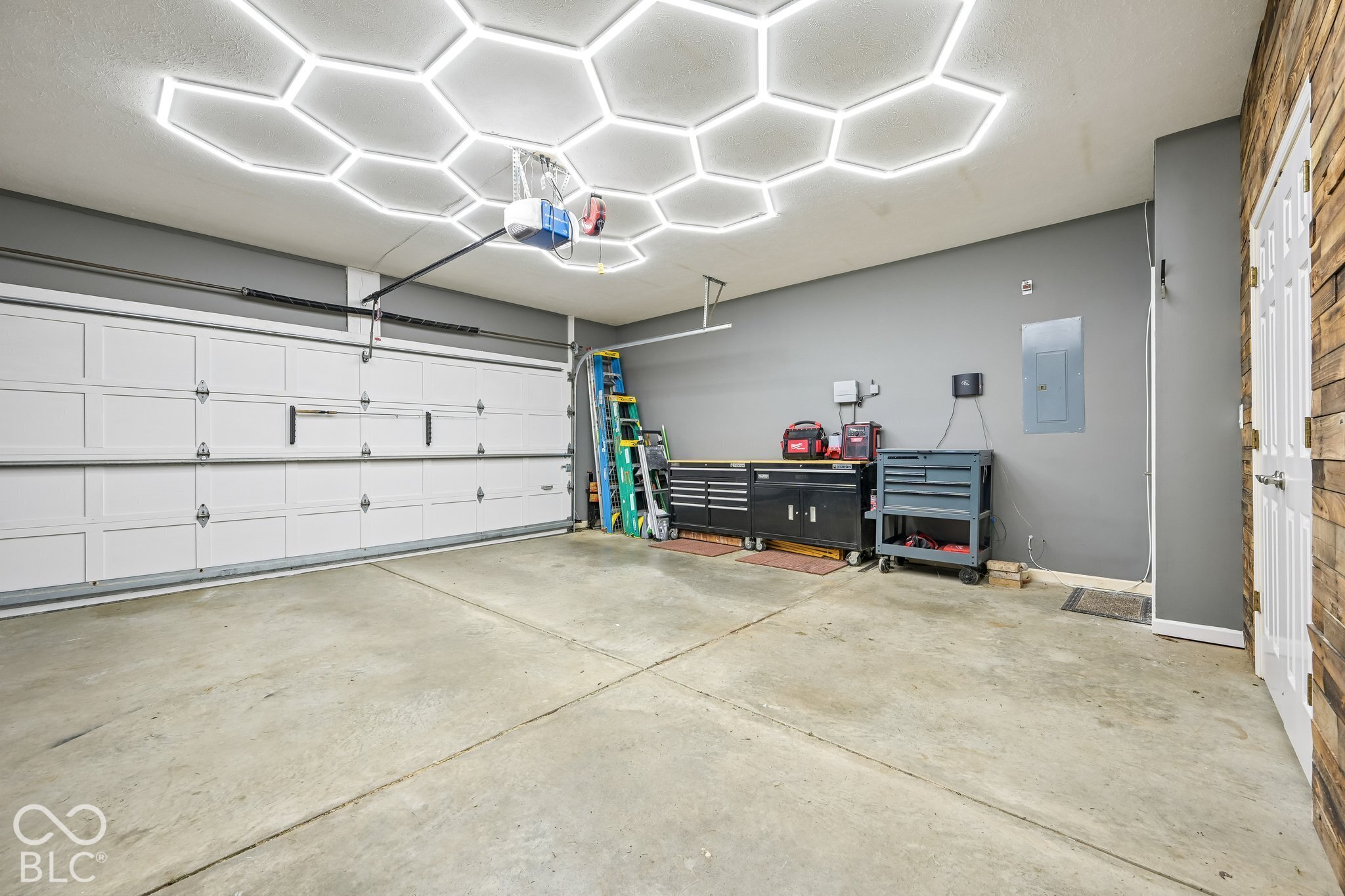 Garage with bright hexagonal ceiling lights, tool cabinets, and a large sectional door.