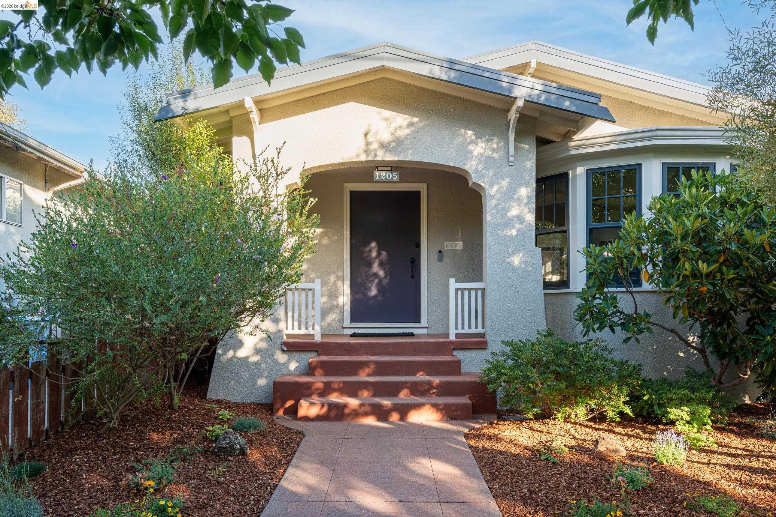 Home entrance with a recessed dark door, broad reddish steps, and landscaped garden.