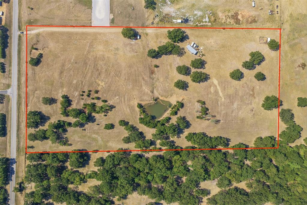 Rural acreage outlined in red, with a pond, scattered trees, and highway frontage.