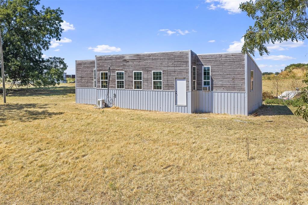 Single-story building with weathered wood-look facade and metal siding on a grassy lot.