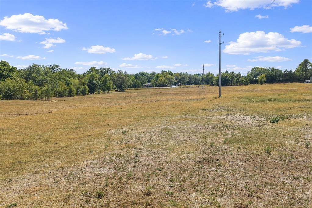 Open grassy property with a distant tree line and utility poles.