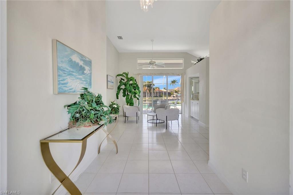 Bright tiled entry hall with a console table, plants, and a pool view through the windows.