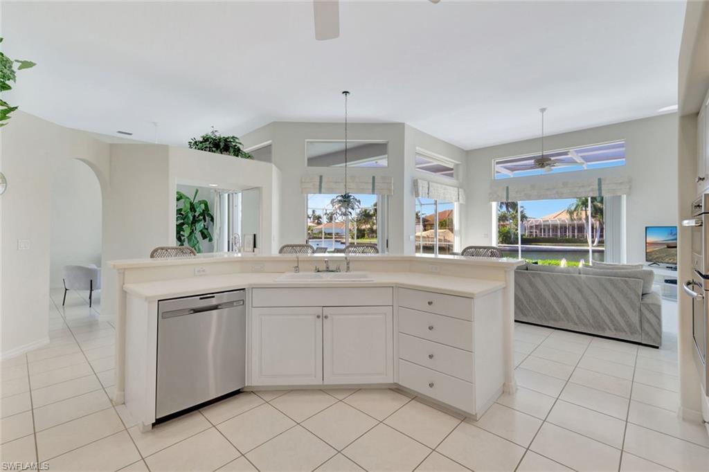 Bright white kitchen with curved breakfast bar and canal views through large windows.