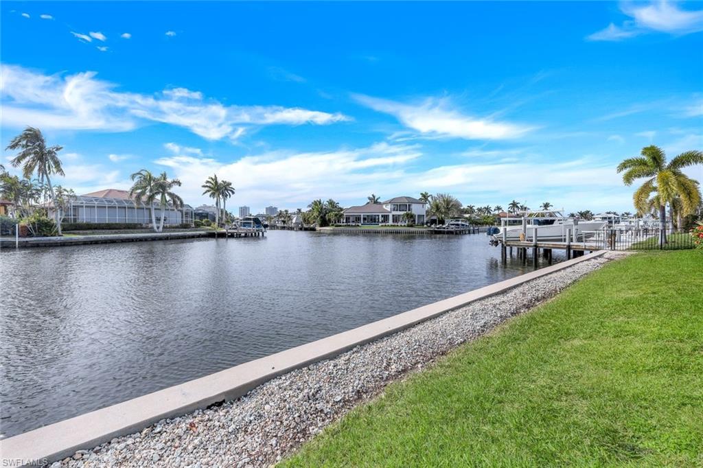 Canal view with waterfront homes, docks, boats, and palms across the water.