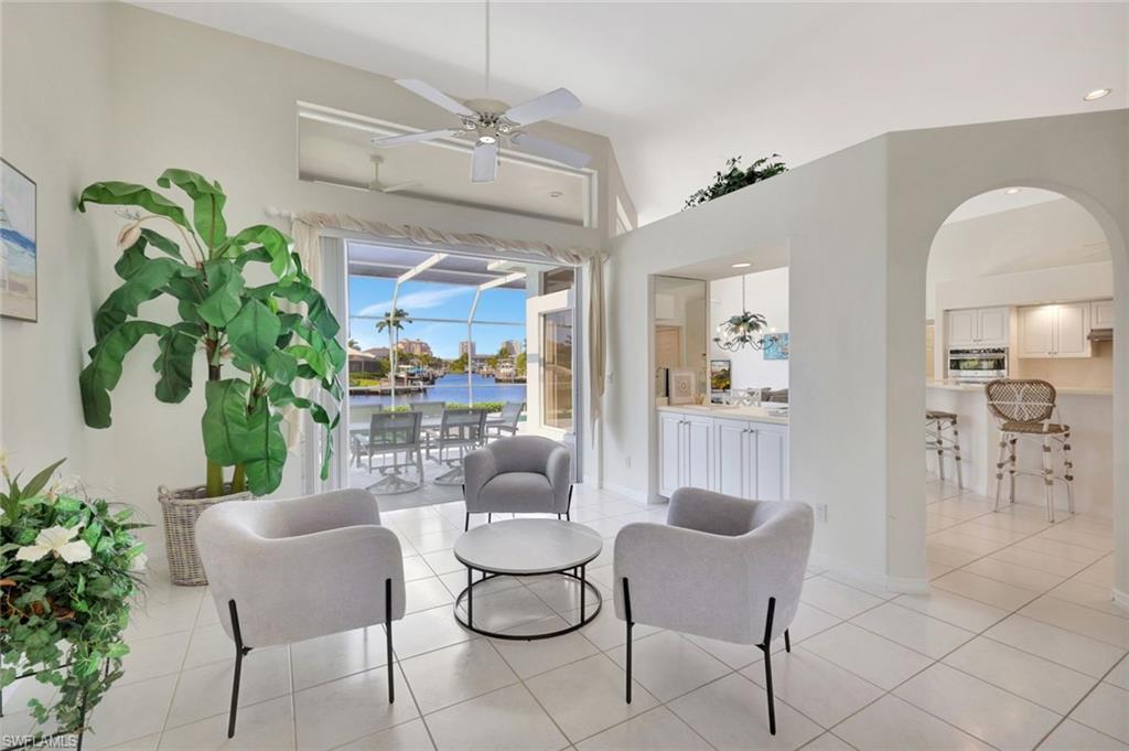 Furnished living room with gray armchairs and canal views through open sliding doors.